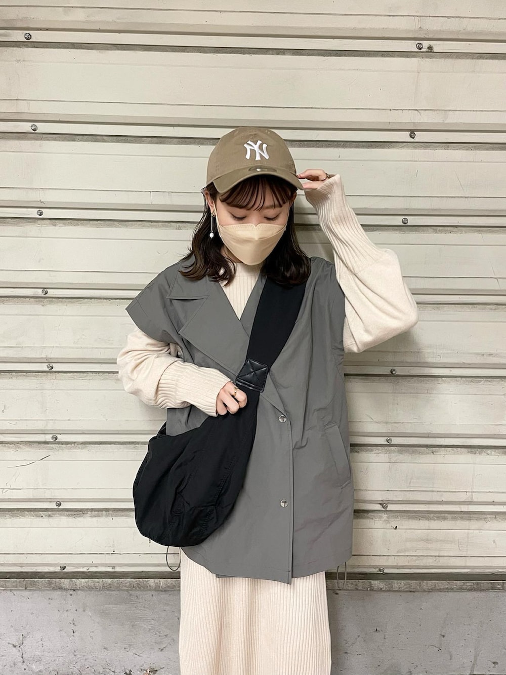 グレー系のミリタリージャケット、ホワイト系のワンピース、ブラック系のショルダーバッグを着用したレディースの春コーディネートの2枚目の写真