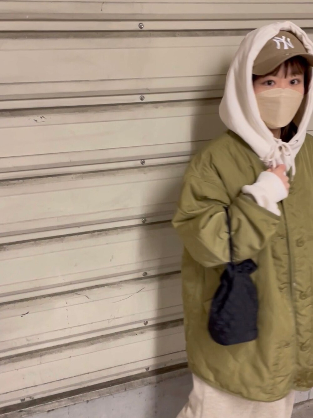 グリーン系のノーカラージャケット、ホワイト系のパーカー、ベージュ系のスカートを着用したレディースの冬コーディネートの3枚目の写真