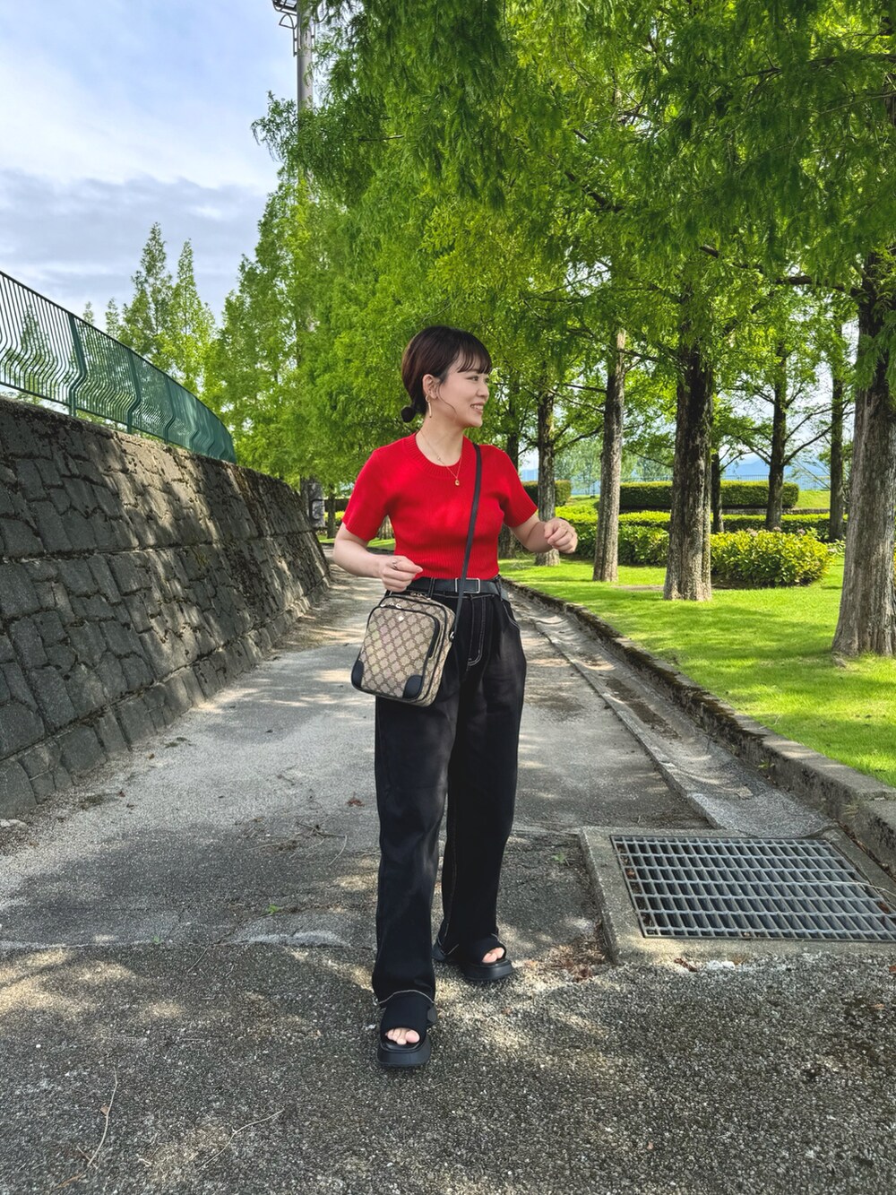 ブラック系のデニムパンツ、レッド系のトップス、ブラック系のショルダーバッグを着用したレディースの夏コーディネートの3枚目の写真