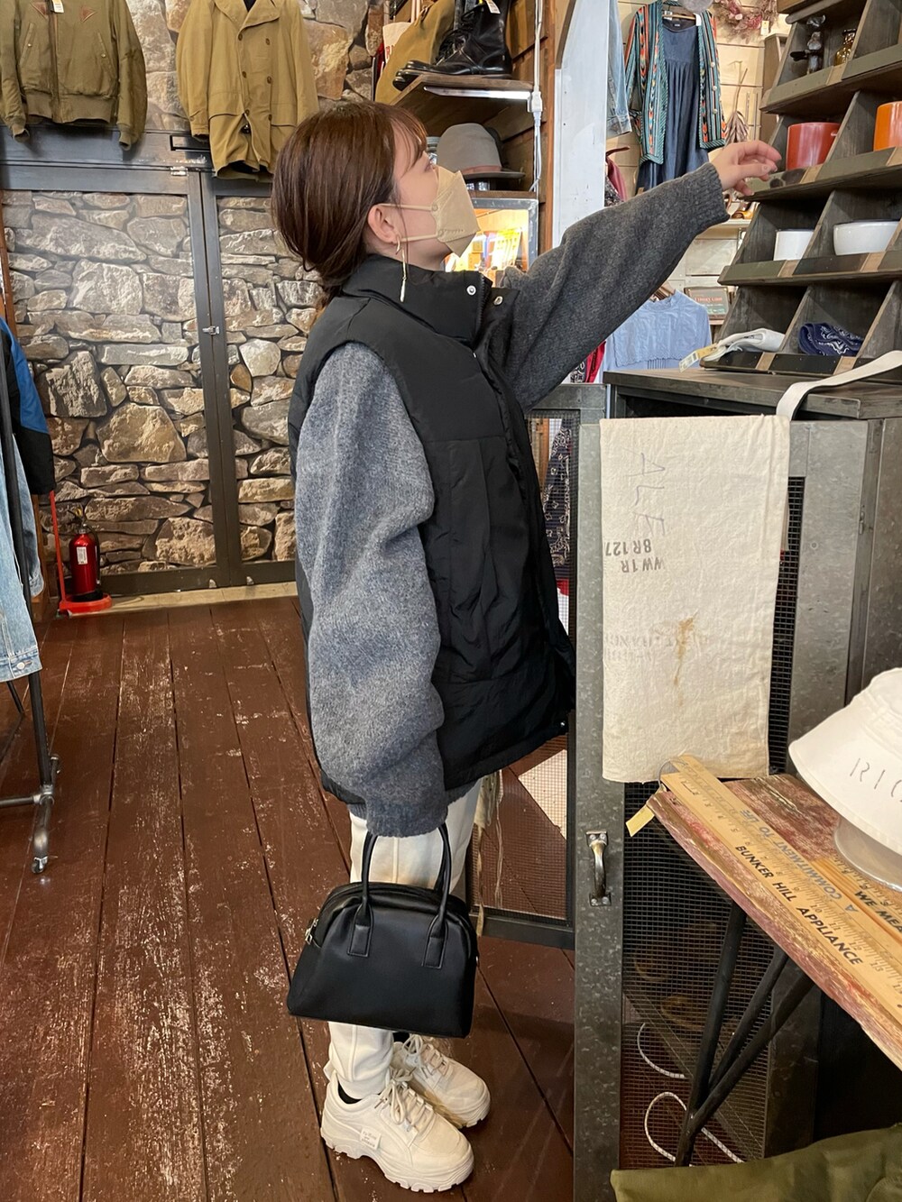 グレー系のニット/セーター、ブラック系のダウンベスト、ホワイト系のパンツを着用したレディースの冬コーディネートの2枚目の写真