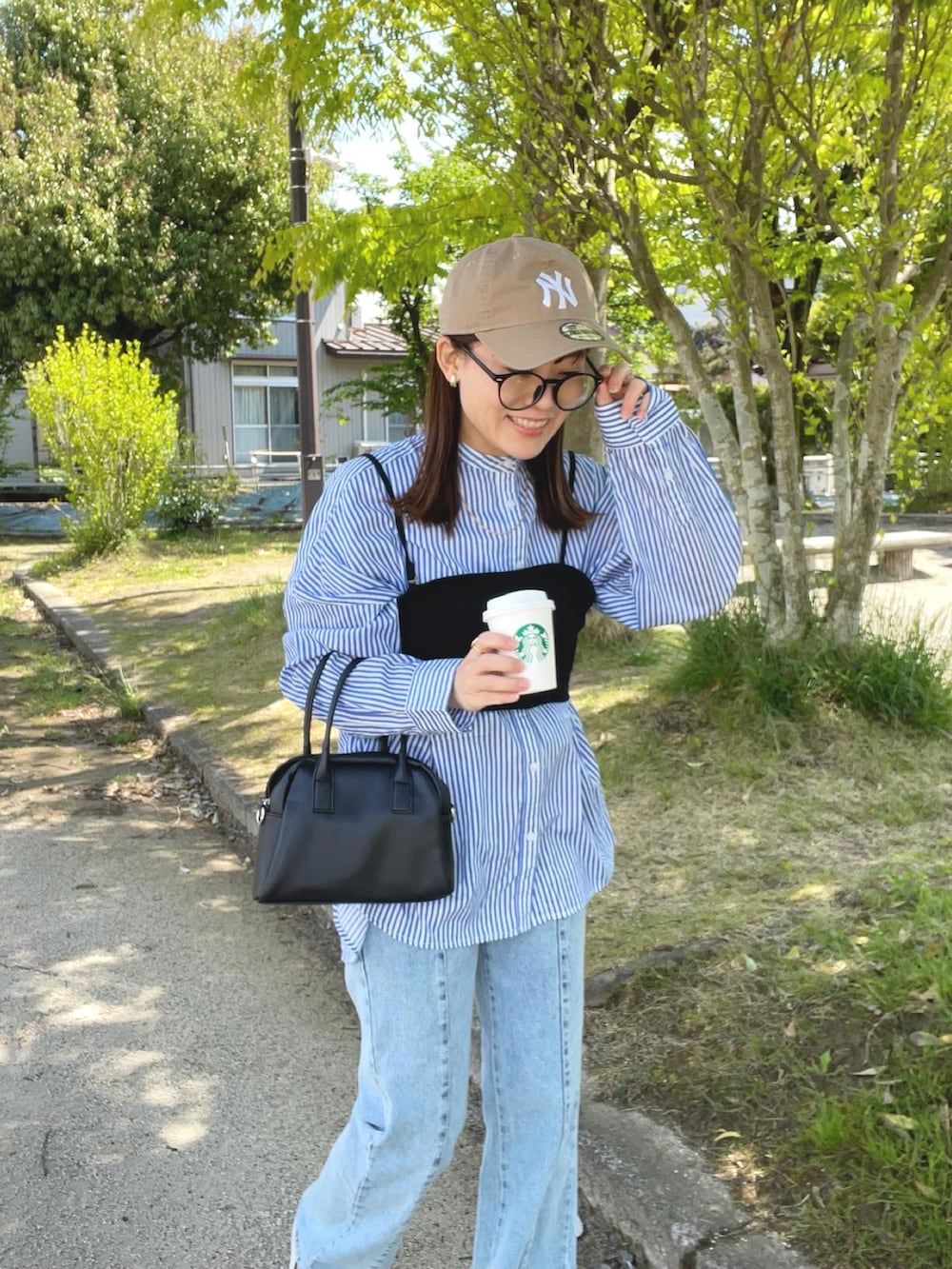 ブルー系のシャツ/ブラウス、ブラック系のその他トップス、ブルー系のデニムパンツを着用したレディースの春コーディネートの2枚目の写真