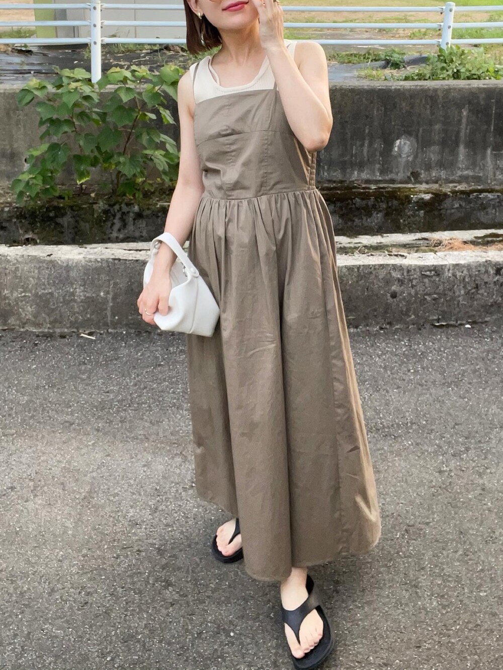 ベージュ系のワンピース、ホワイト系のハンドバッグ、ブラック系のサンダルを着用したレディースの夏コーディネートの5枚目の写真