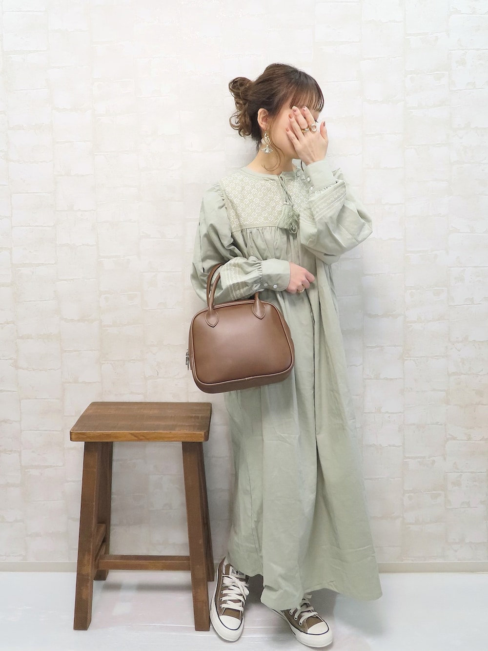 グリーン系のワンピース、ベージュ系のベスト、ブラウン系のショルダーバッグを着用したレディースの春コーディネートの3枚目の写真