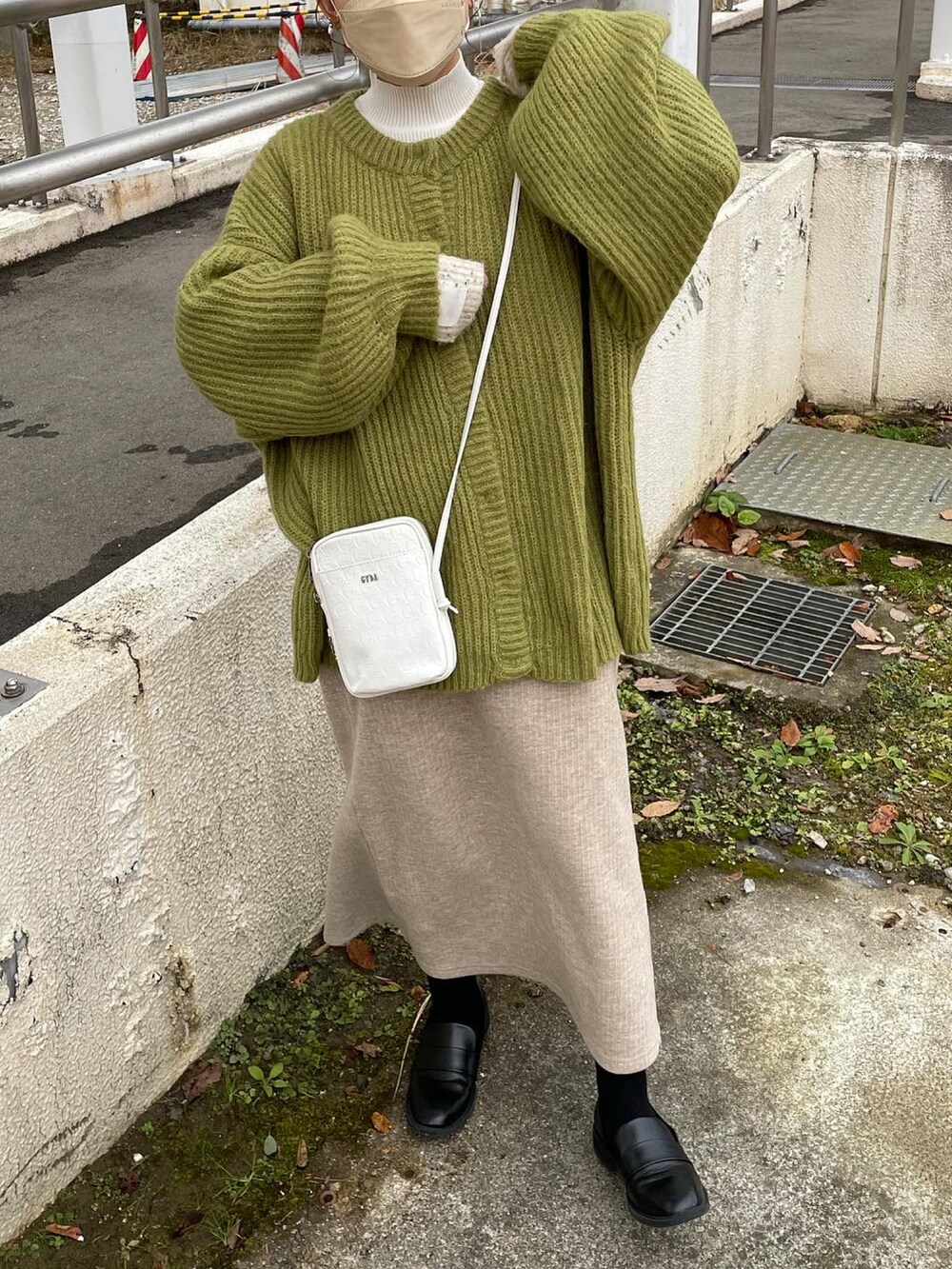 ホワイト系のショルダーバッグ、ホワイト系のニット/セーター、グリーン系のカーディガン/ボレロを着用したレディースの冬コーディネートの2枚目の写真