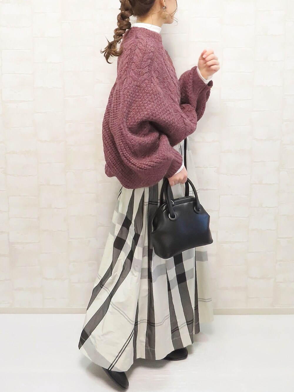 ホワイト系のスカート、パープル系のニット/セーター、ホワイト系のTシャツ/カットソーを着用したレディースの冬コーディネートの3枚目の写真