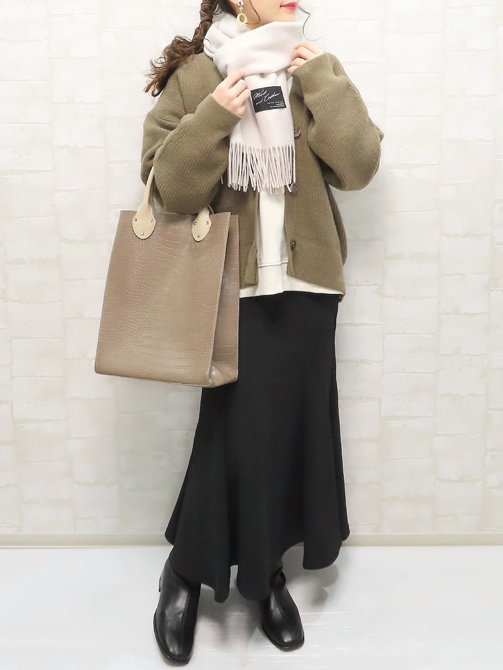 ブラウン系のトートバッグ、ブラウン系のカーディガン/ボレロ、ホワイト系のスウェットを着用したレディースの冬コーディネートの2枚目の写真