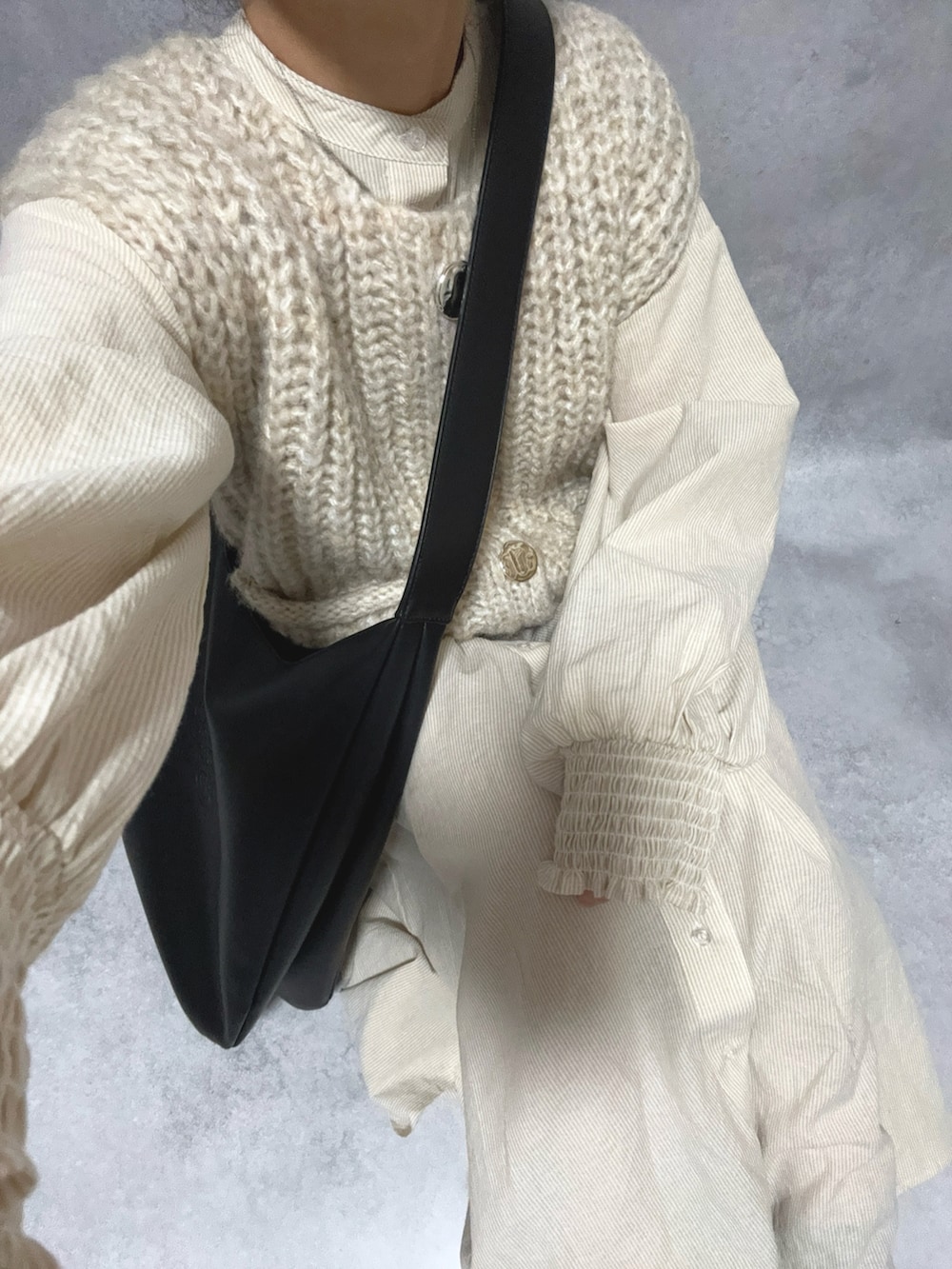 ベージュ系のシャツワンピース、ホワイト系のトップス、ブラック系のバッグを着用したレディースの冬コーディネートの4枚目の写真