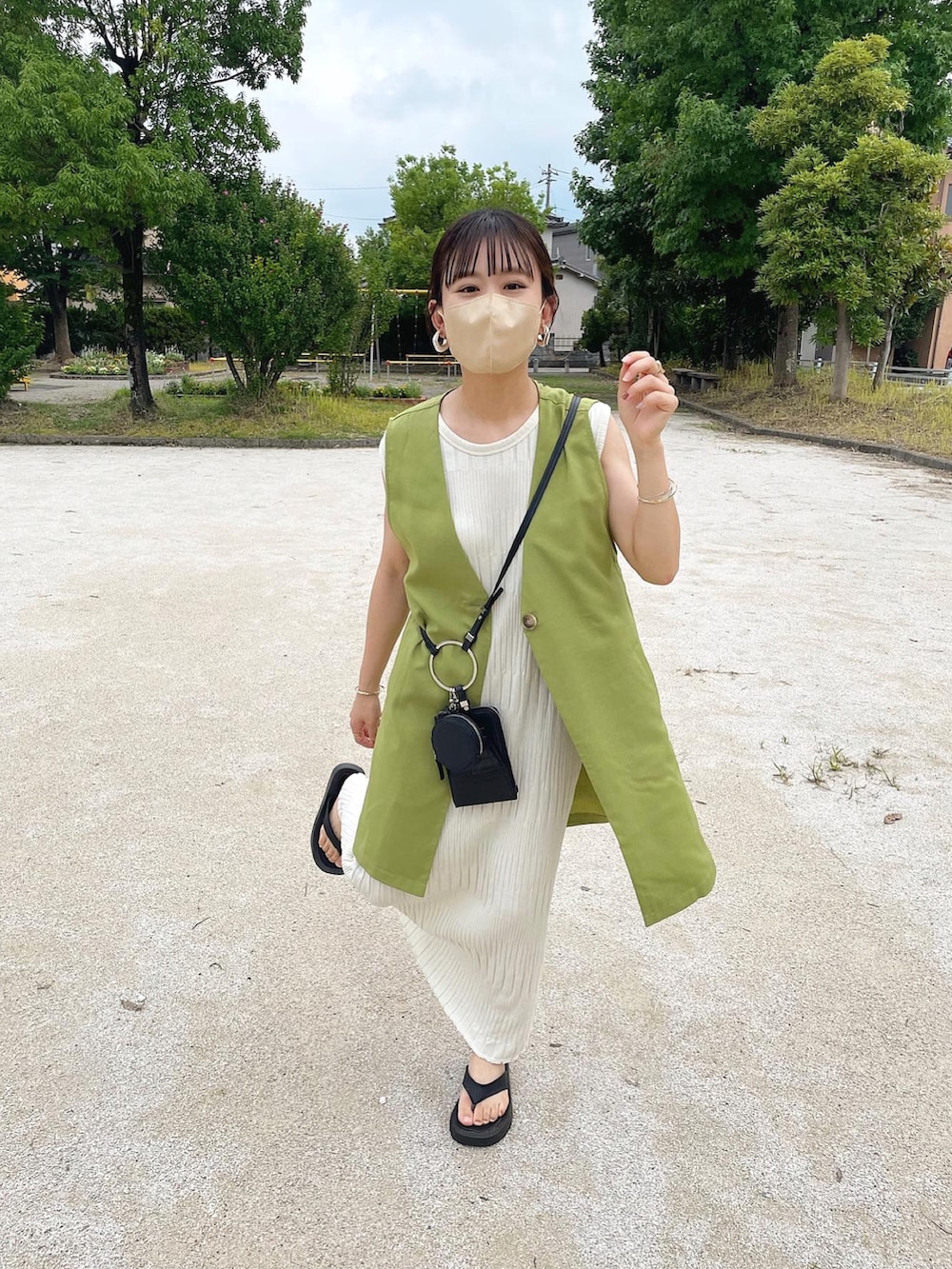 グリーン系のベスト、ホワイト系のワンピース、ブラック系のサンダルを着用したレディースの夏コーディネートの3枚目の写真