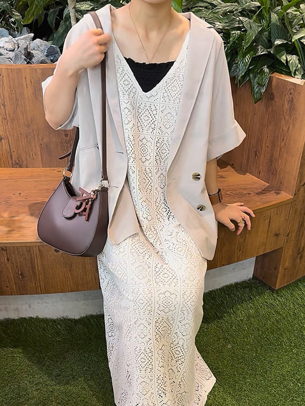 ホワイト系のワンピース、ブラウン系のバッグ、ブラウン系のキーホルダーを着用したレディースの夏コーディネートの2枚目の写真