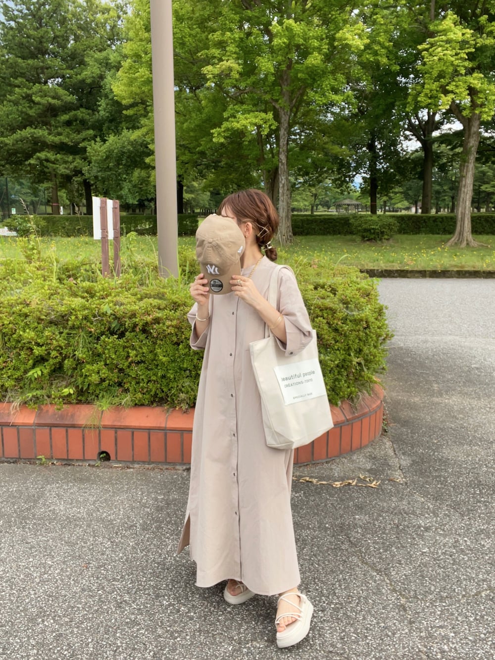 グレー系のシャツワンピース、ホワイト系のトートバッグ、ホワイト系のサンダルを着用したレディースの夏コーディネートの5枚目の写真