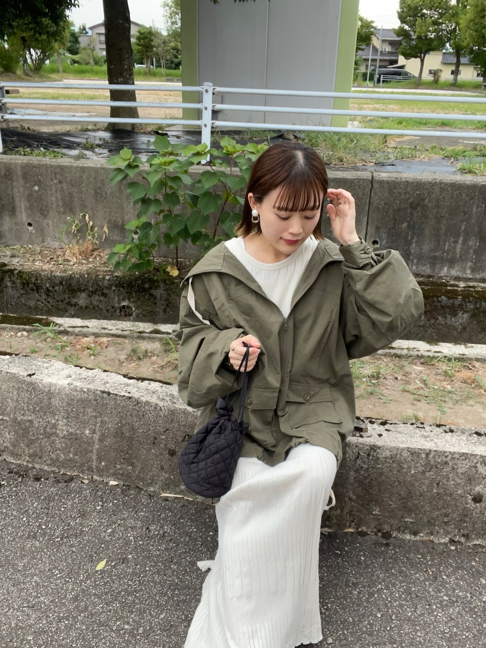 グリーン系のマウンテンパーカー、ホワイト系のワンピース、ブラック系のショルダーバッグを着用したレディースの夏コーディネートの5枚目の写真
