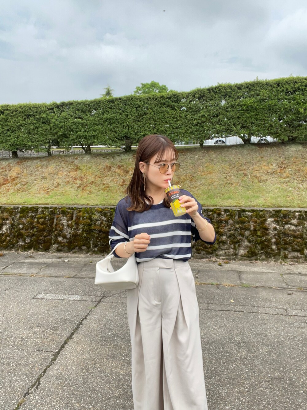 ブルー系のTシャツ/カットソー、ホワイト系のスラックス、ホワイト系のハンドバッグを着用したレディースの夏コーディネートの3枚目の写真