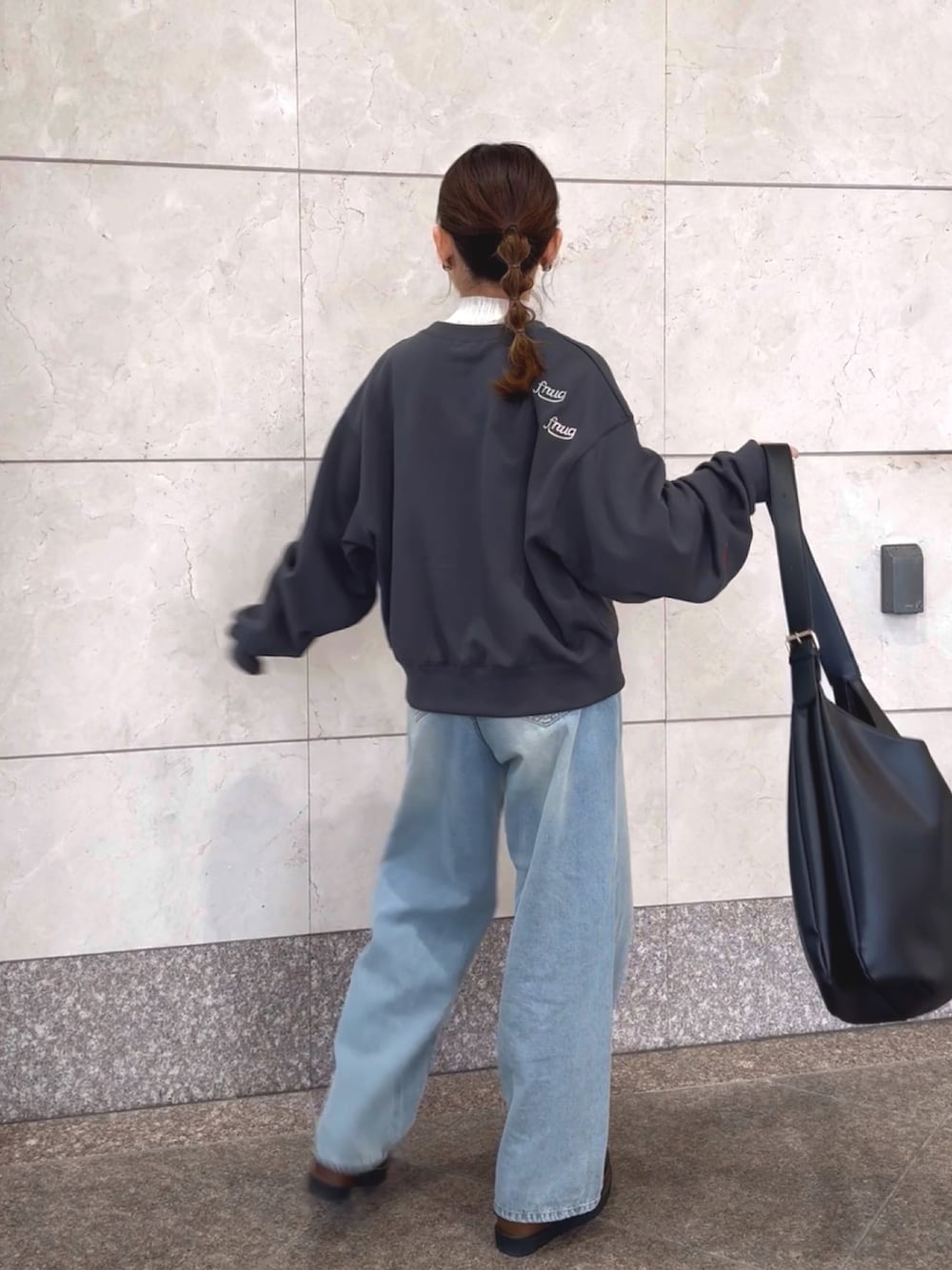 グレー系のスウェット、ホワイト系のニット/セーター、ブルー系のデニムパンツを着用したレディースの冬コーディネートの2枚目の写真