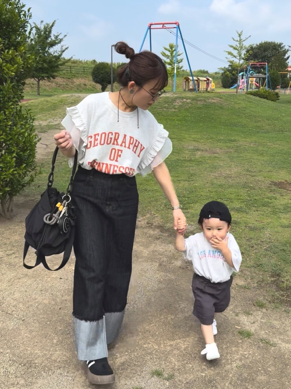 ベージュ系のTシャツ/カットソー、ブラック系のデニムスカート、ブラック系のバッグを着用したレディースの夏コーディネートの3枚目の写真