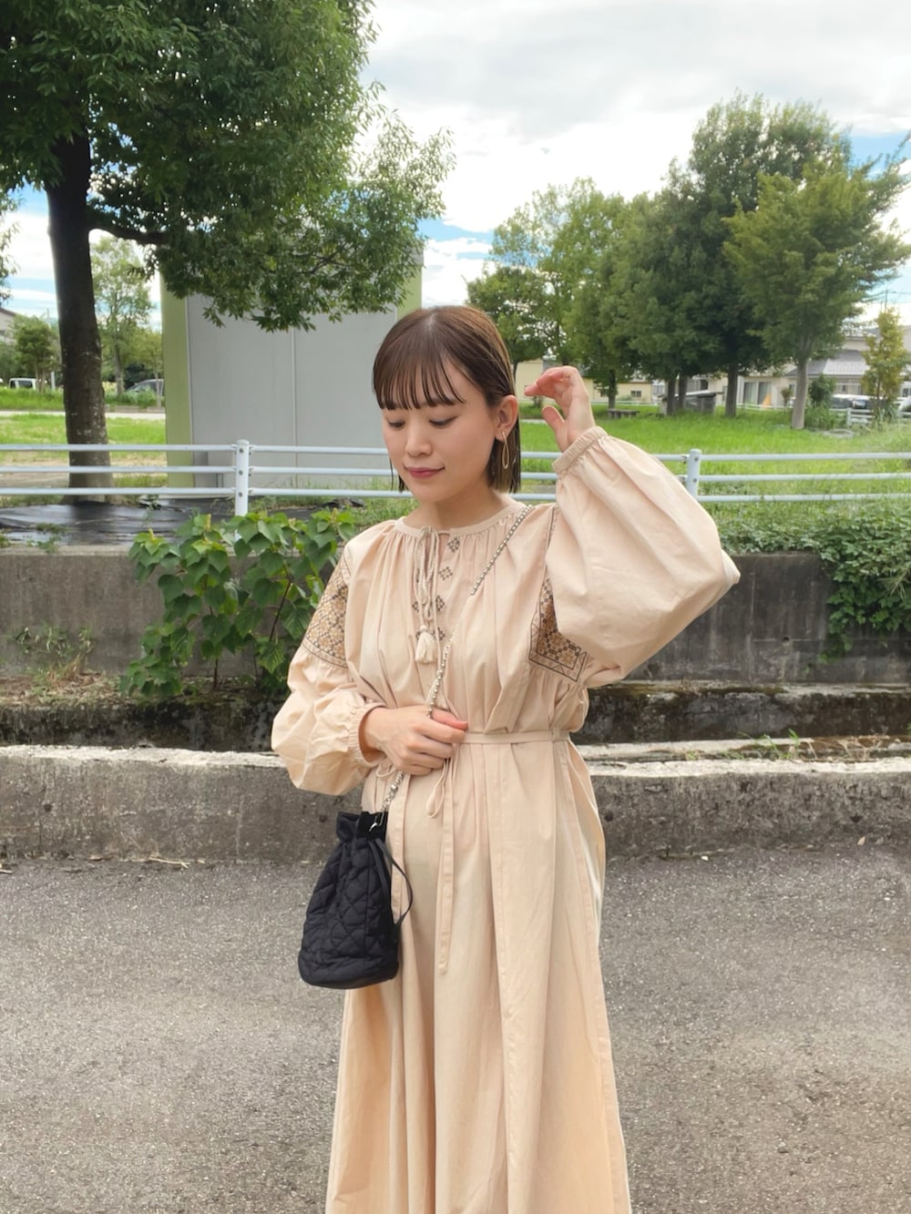 ベージュ系のワンピース、ブラック系のショルダーバッグ、ブラック系のブーツを着用したレディースの秋コーディネートの3枚目の写真