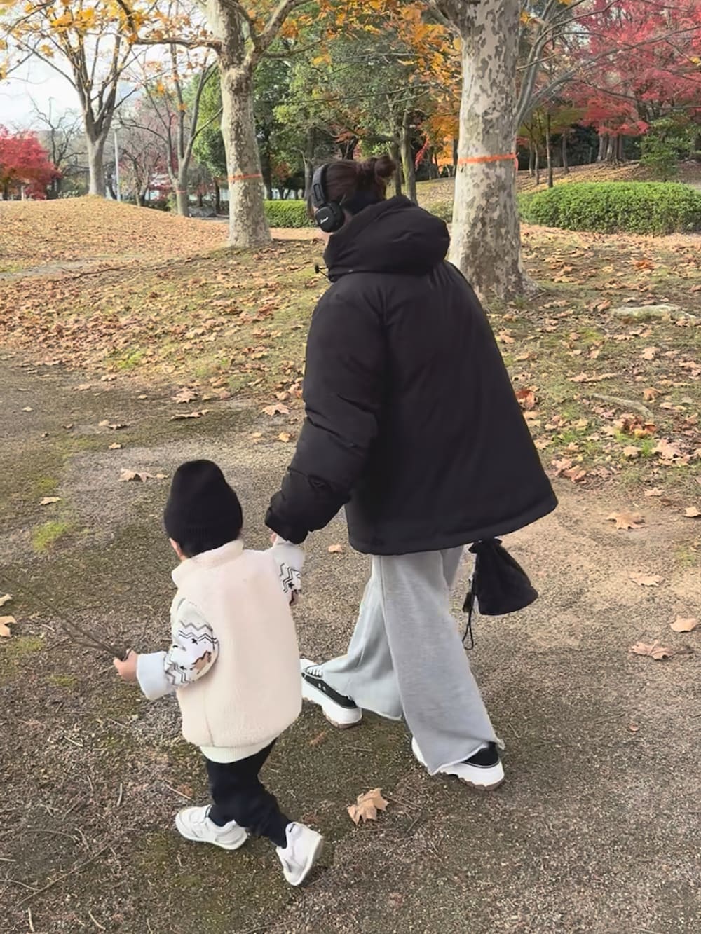 グレー系のニット/セーター、ブラック系のダウンジャケット/コート、グレー系のスウェットパンツを着用したレディースの冬コーディネートの3枚目の写真