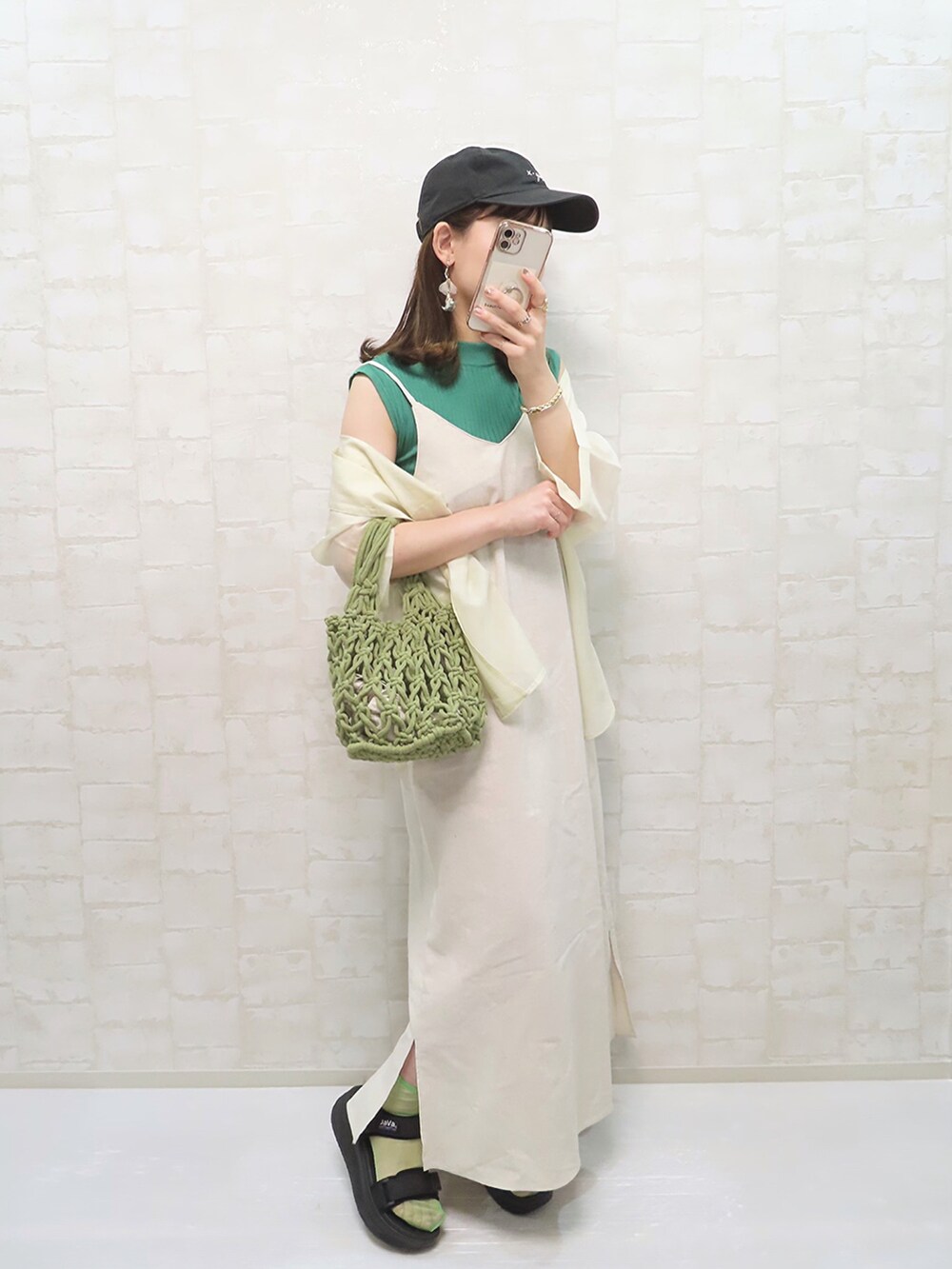 グリーン系のワンピース、グリーン系のハンドバッグ、グリーン系のニット/セーターを着用したレディースの春コーディネートの2枚目の写真