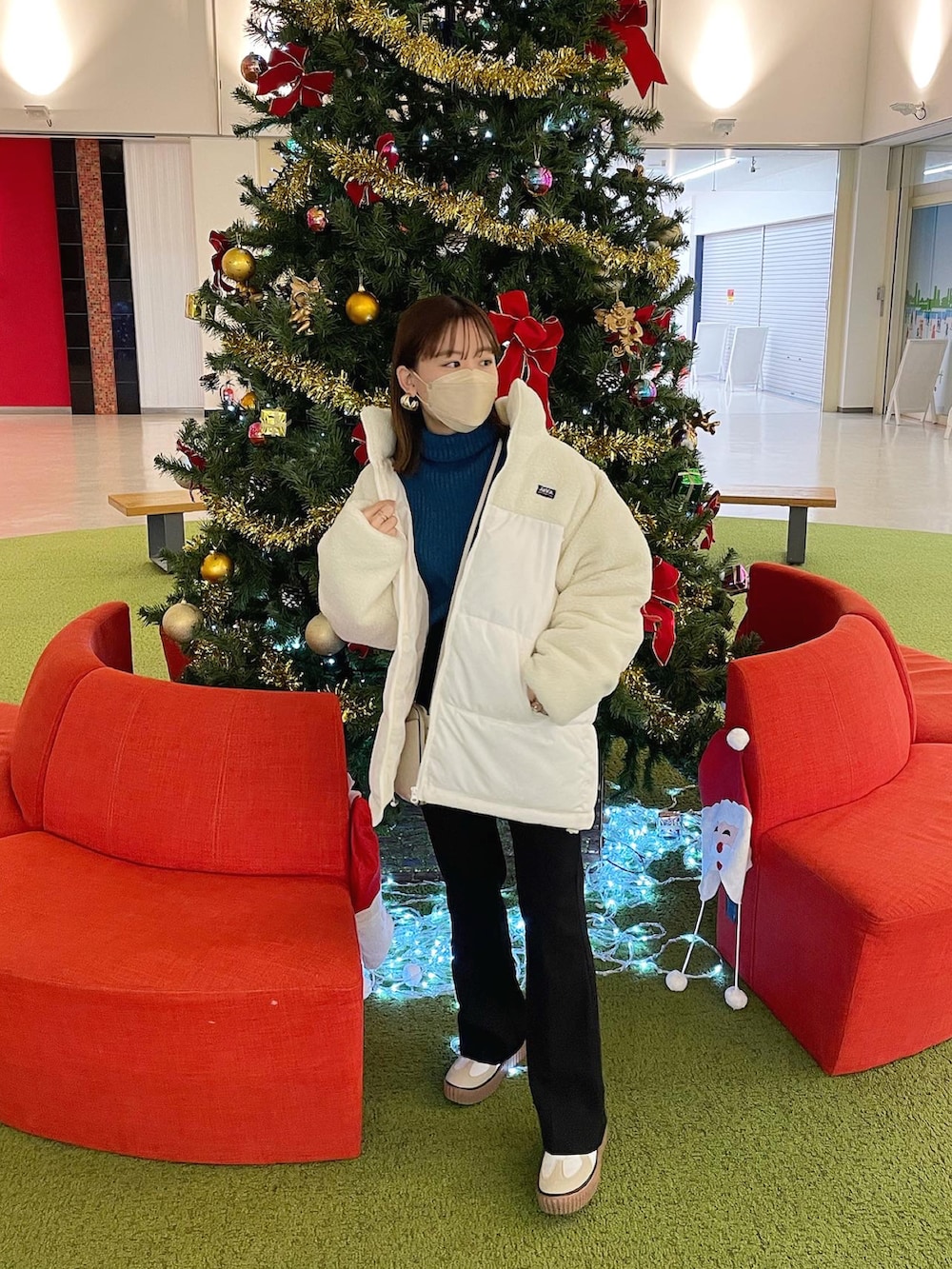 ホワイト系のダウンジャケット/コート、ブルー系のニット/セーター、ブラック系のスラックスを着用したレディースの冬コーディネートの4枚目の写真