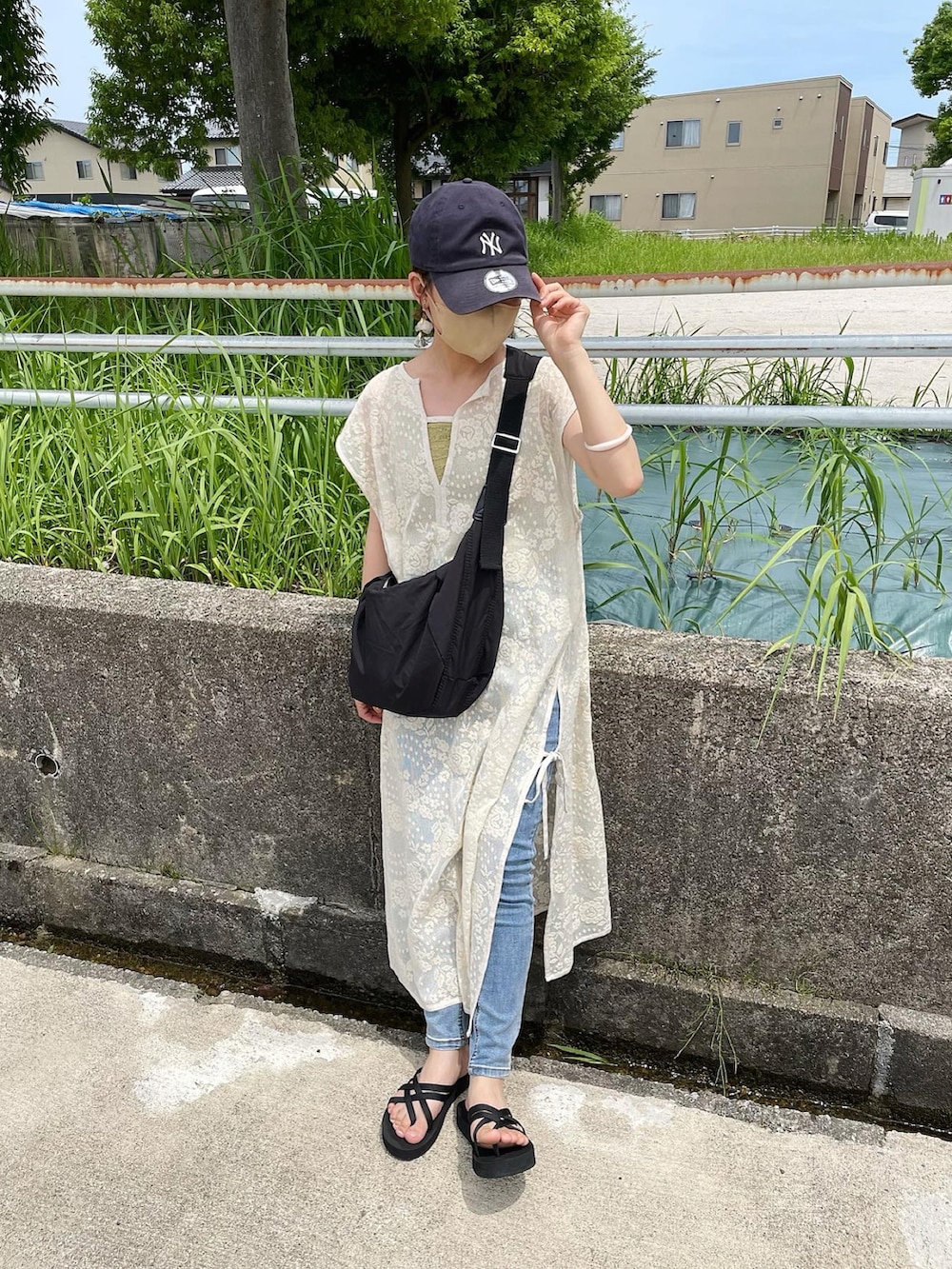 ホワイト系のワンピース、ブラック系のショルダーバッグ、ブラック系のサンダルを着用したレディースの夏コーディネートの4枚目の写真
