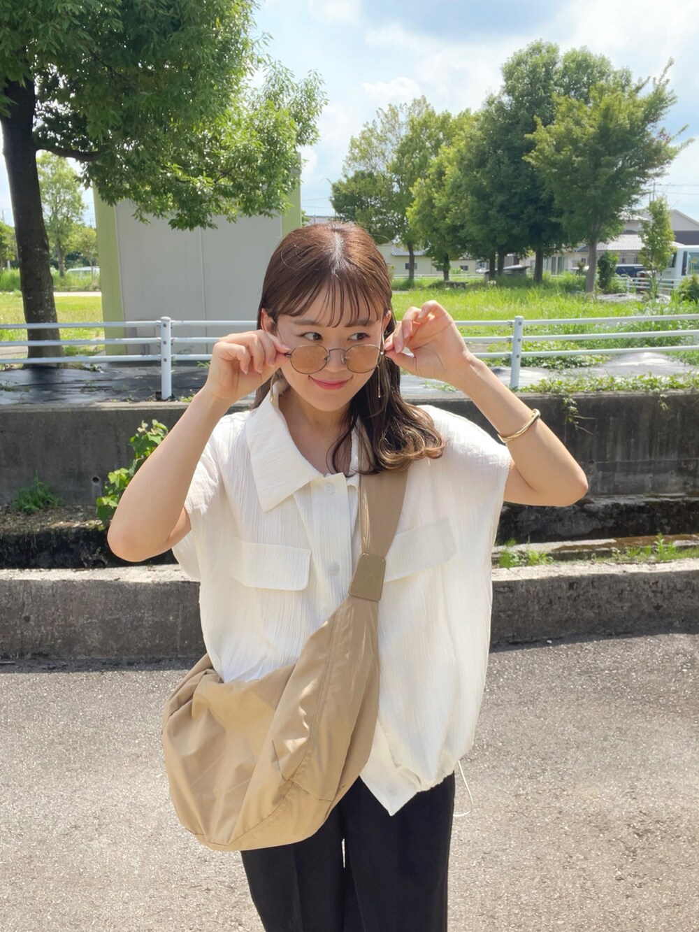 ベージュ系のショルダーバッグ、ブラック系のパンツ、ブラック系のサンダルを着用したレディースの夏コーディネートの3枚目の写真