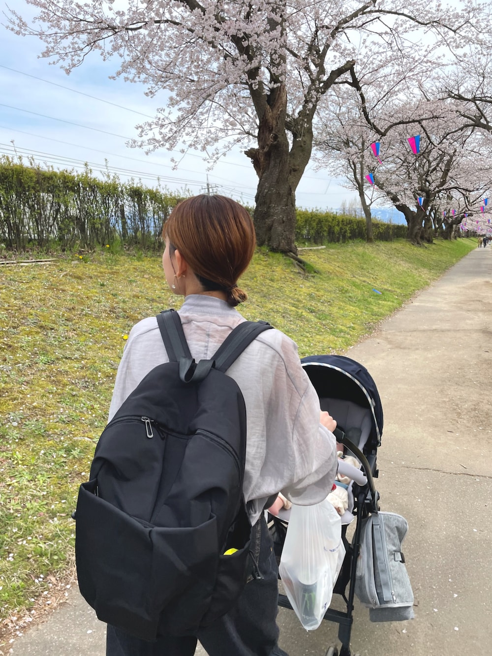 グレー系のブルゾン、ブラック系のバックパック/リュック、ブラック系のデニムパンツを着用したレディースの春コーディネートの3枚目の写真