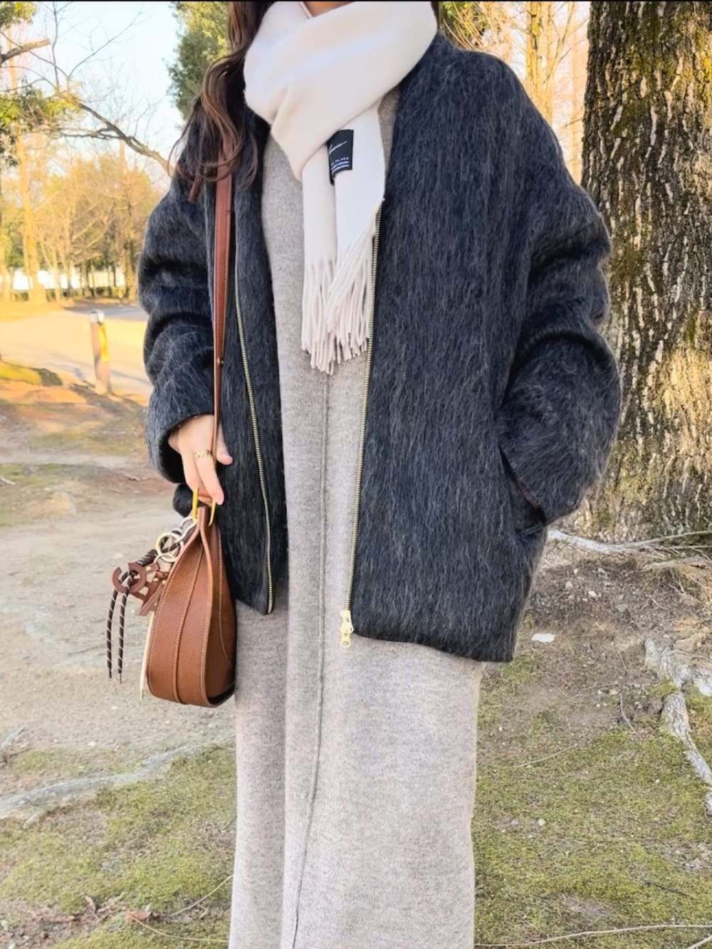 ブラック系のノーカラーコート、ベージュ系のワンピース、ブラック系のシューズを着用したレディースの冬コーディネートの3枚目の写真