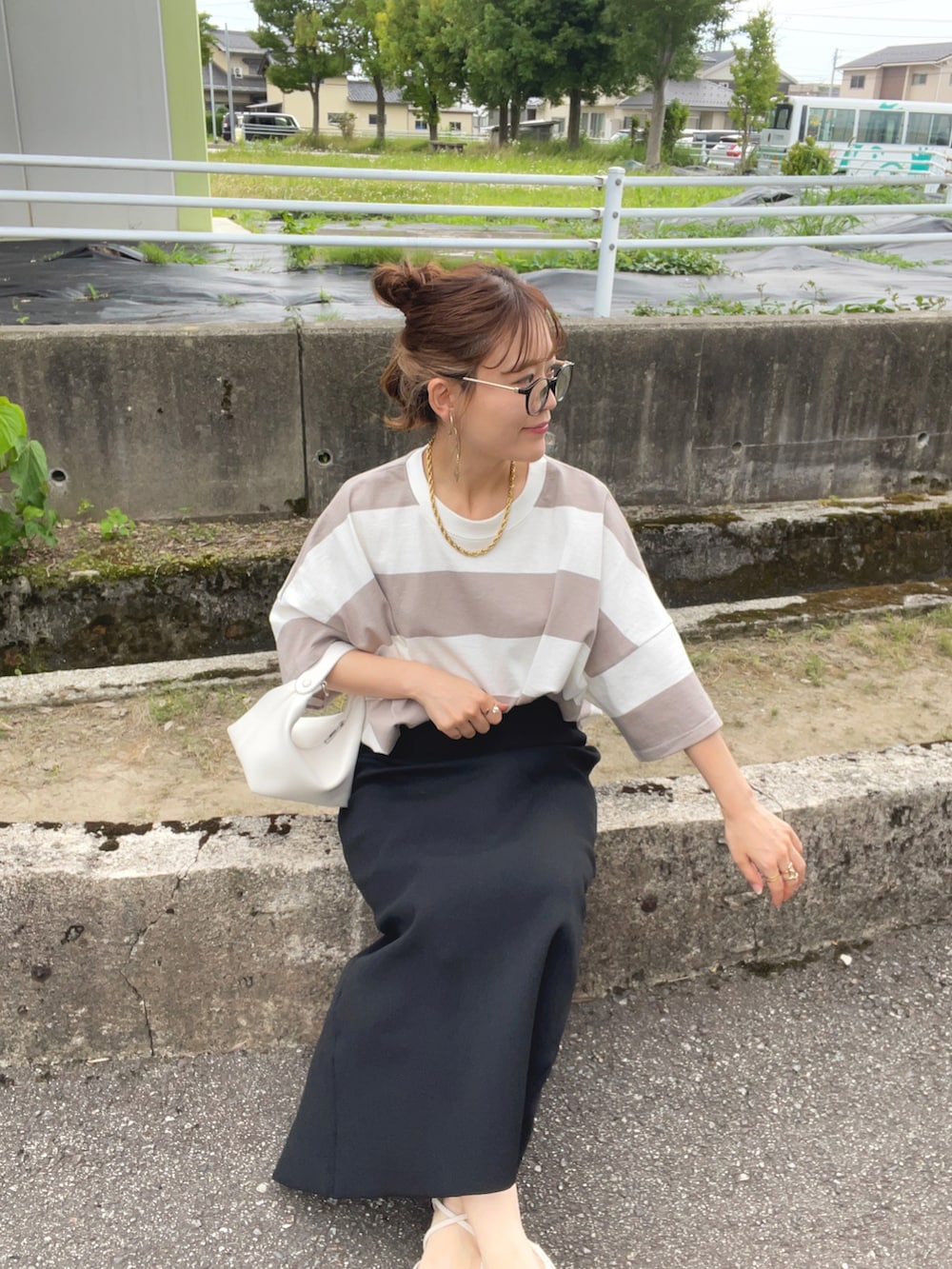 ベージュ系のTシャツ/カットソー、ブラック系のスカート、ホワイト系のハンドバッグを着用したレディースの夏コーディネートの5枚目の写真