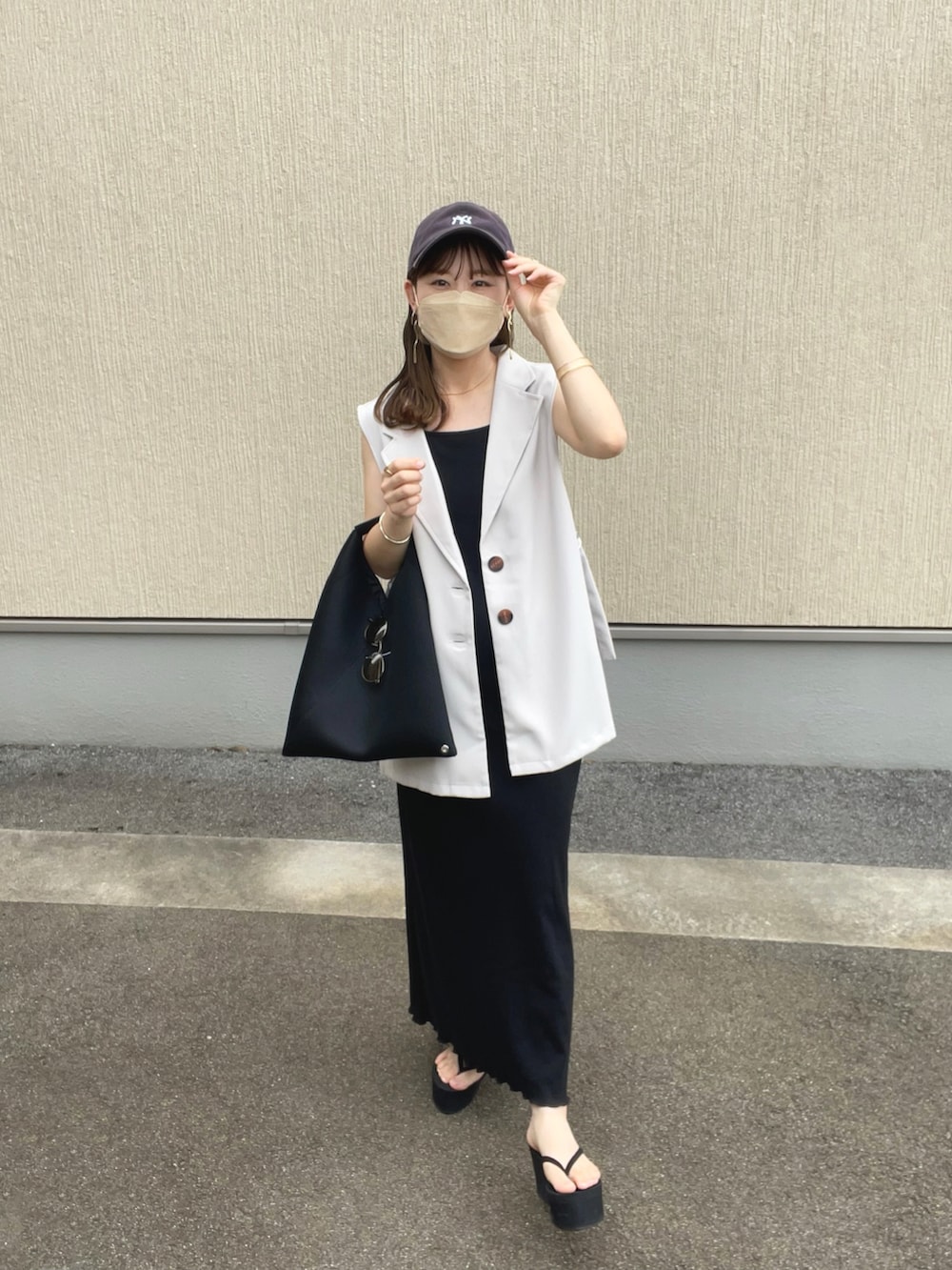 ベージュ系のベスト、ブラック系のワンピース、ブラック系のトートバッグを着用したレディースの夏コーディネートの5枚目の写真