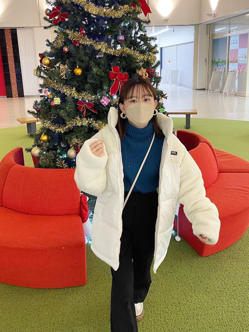 ホワイト系のダウンジャケット/コート、ブルー系のニット/セーター、ブラック系のスラックスを着用したレディースの冬コーディネートの2枚目の写真