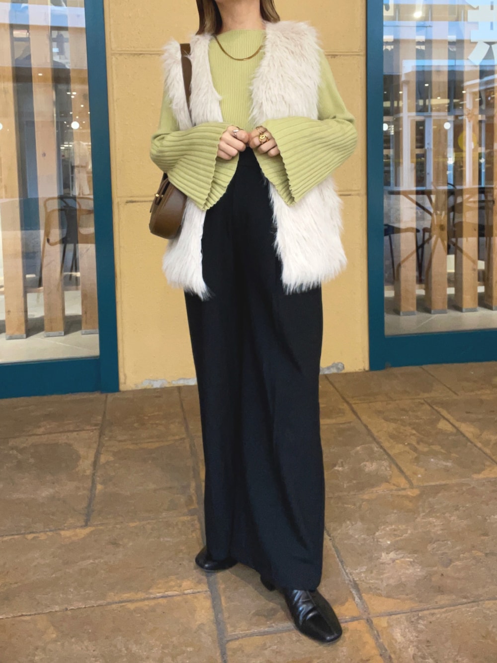 グリーン系のニット/セーター、ホワイト系のベスト、ブラック系のパンツを着用したレディースの秋コーディネートの2枚目の写真