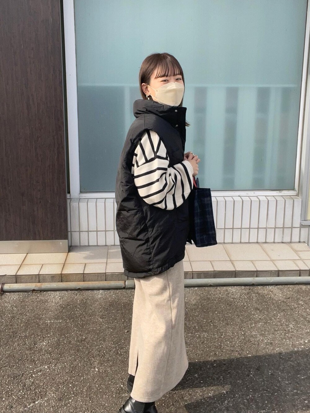 ホワイト系のニット/セーター、ブルー系のトートバッグ、ブラック系のダウンベストを着用したレディースの秋コーディネートの2枚目の写真