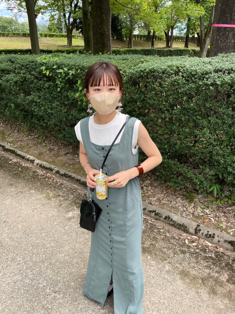 グリーン系のワンピース、ホワイト系のニット/セーター、ブラック系のショルダーバッグを着用したレディースの夏コーディネートの2枚目の写真