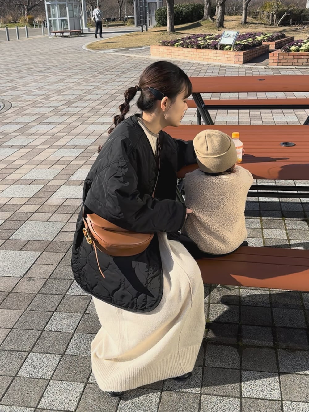 ブラック系のノーカラージャケット、ホワイト系のワンピース、ブラウン系のハンドバッグを着用したレディースの冬コーディネートの3枚目の写真