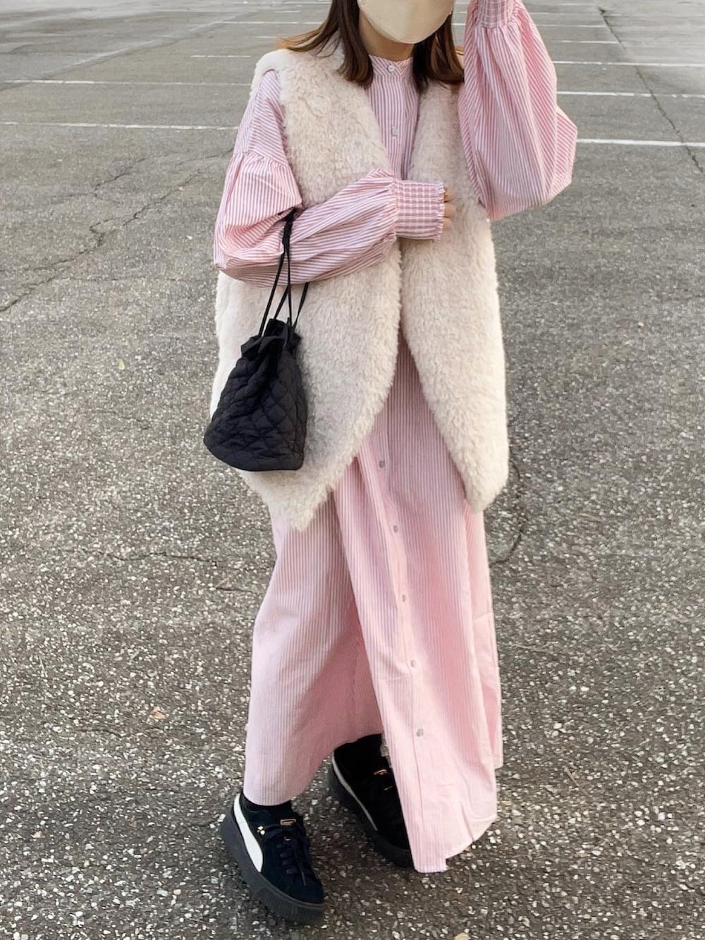 レッド系のワンピース、グレー系のベスト、ブラック系のショルダーバッグを着用したレディースの冬コーディネートの5枚目の写真