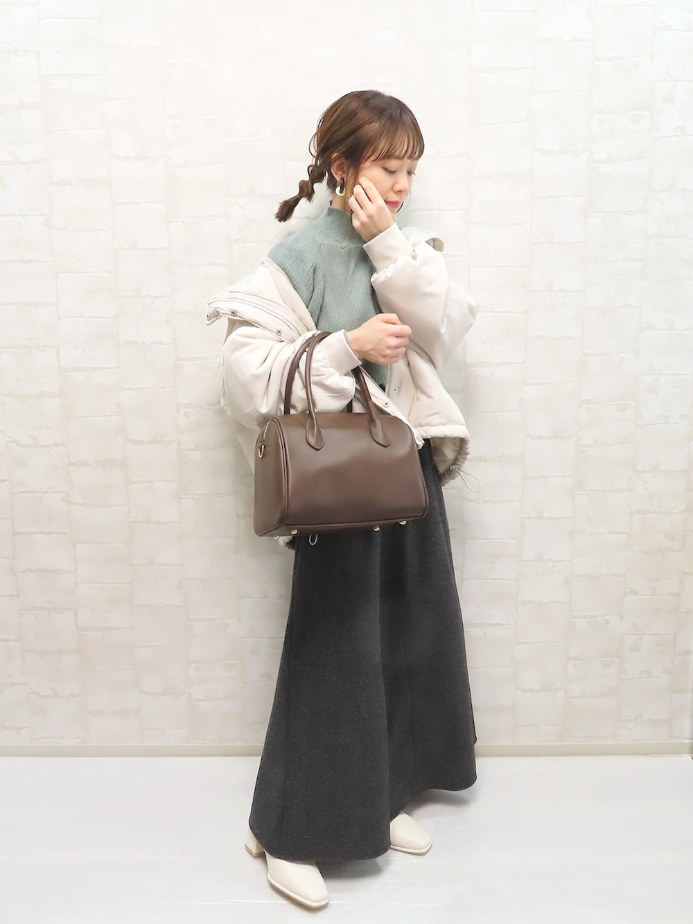 グリーン系のニット/セーター、ホワイト系のパーカー、グレー系のスカートを着用したレディースの冬コーディネートの2枚目の写真