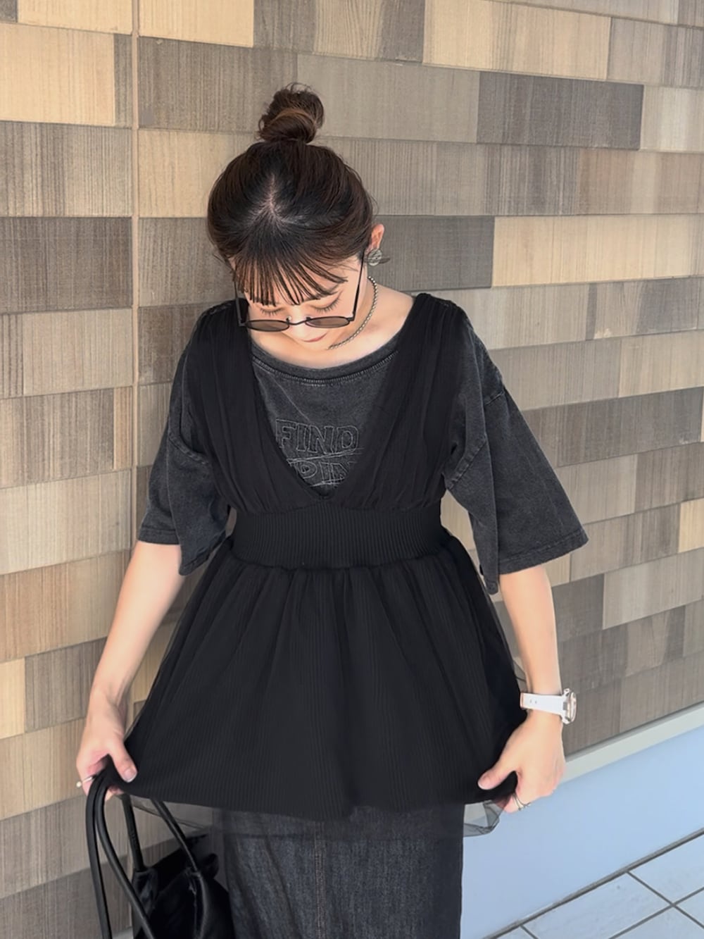 ブラック系のデニムスカート、グレー系のTシャツ/カットソー、ブラック系のベストを着用したレディースの秋コーディネートの3枚目の写真