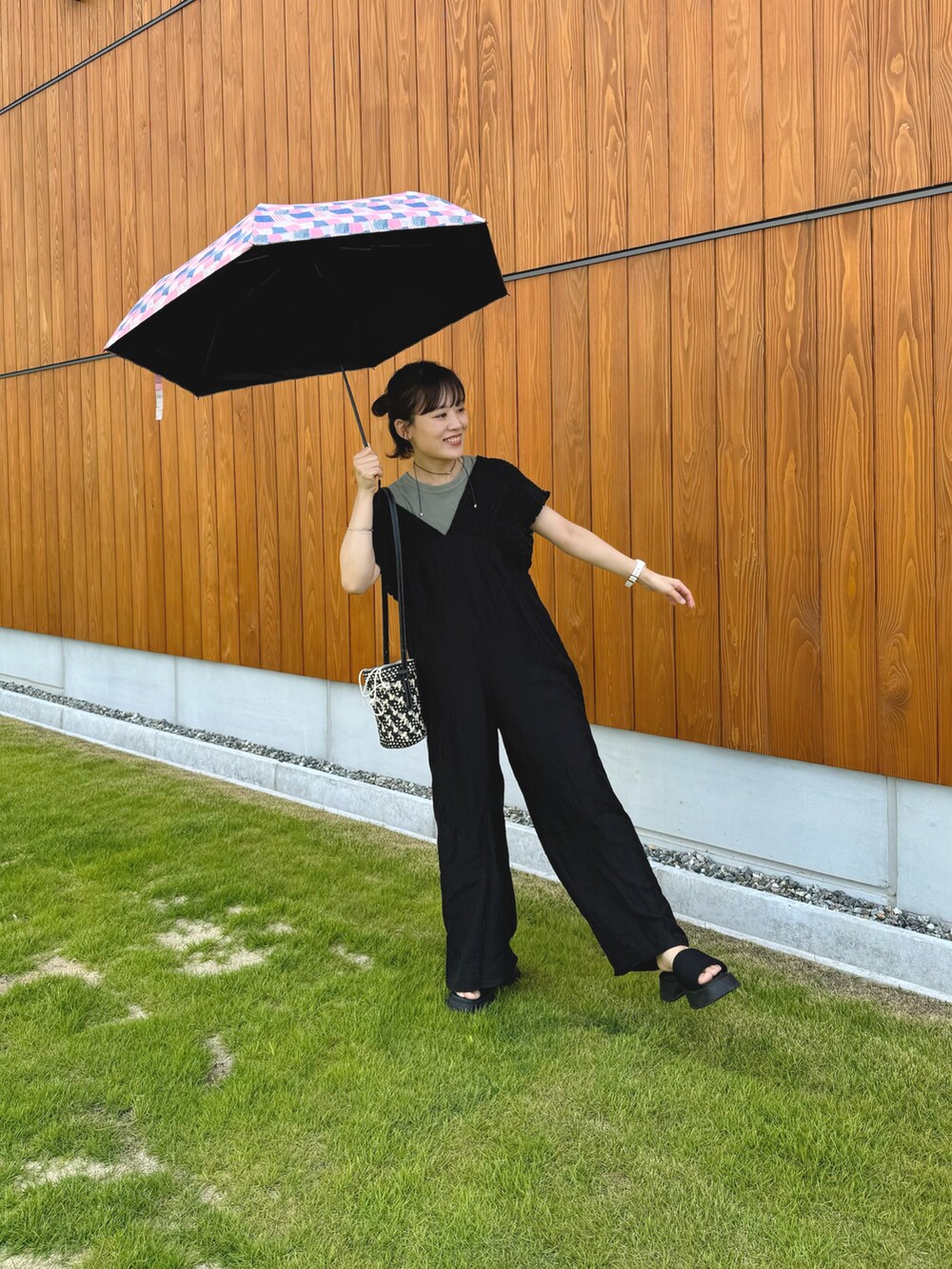 グリーン系のトップス、ブラック系のつなぎ/オールインワン、ブラック系のショルダーバッグを着用したレディースの夏コーディネートの2枚目の写真