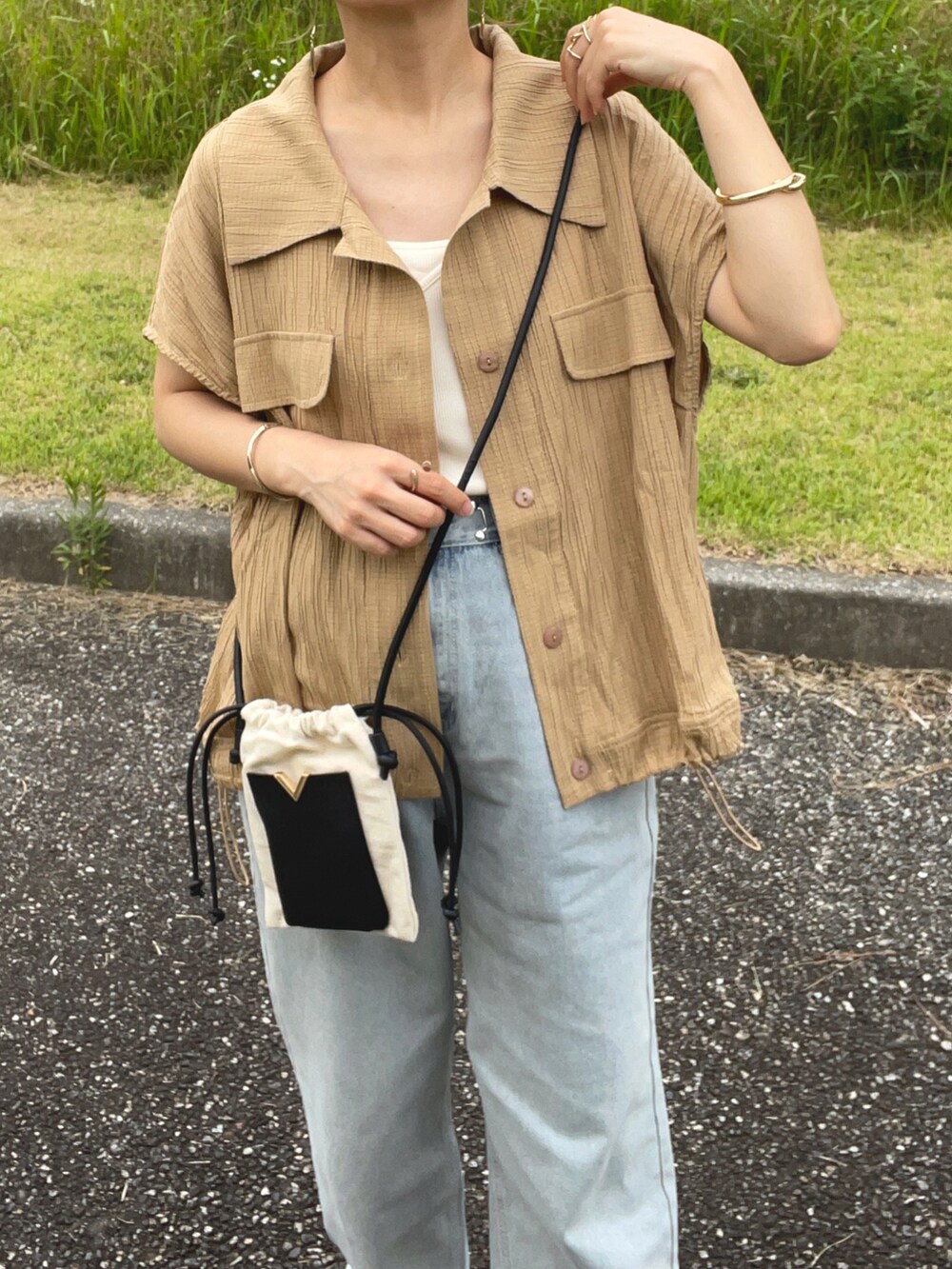 ブラウン系のシャツ/ブラウス、ブルー系のデニムパンツ、ホワイト系のショルダーバッグを着用したレディースの夏コーディネートの3枚目の写真