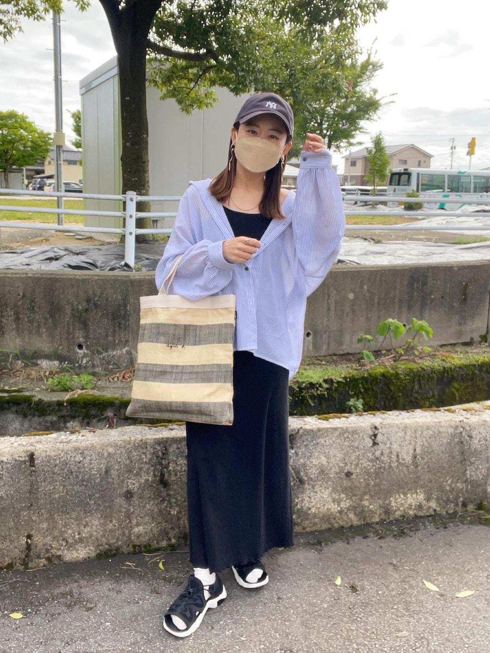 ブラック系のトートバッグ、ブルー系のシャツ/ブラウス、ブラック系のワンピースを着用したレディースの春コーディネートの2枚目の写真