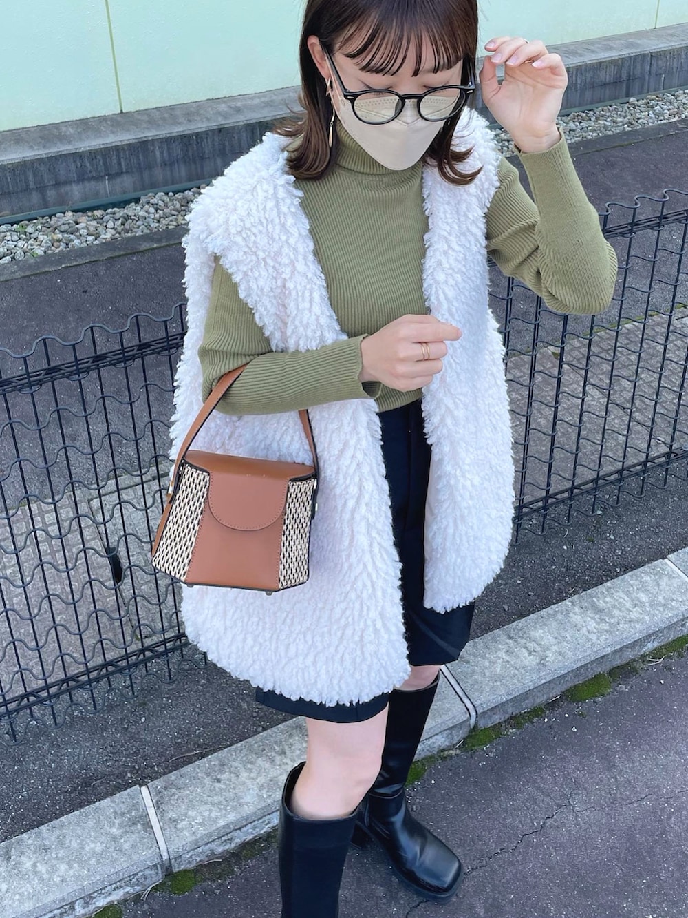 ホワイト系のベスト、グリーン系のニット/セーター、ブラック系のスラックスを着用したレディースの秋コーディネートの2枚目の写真