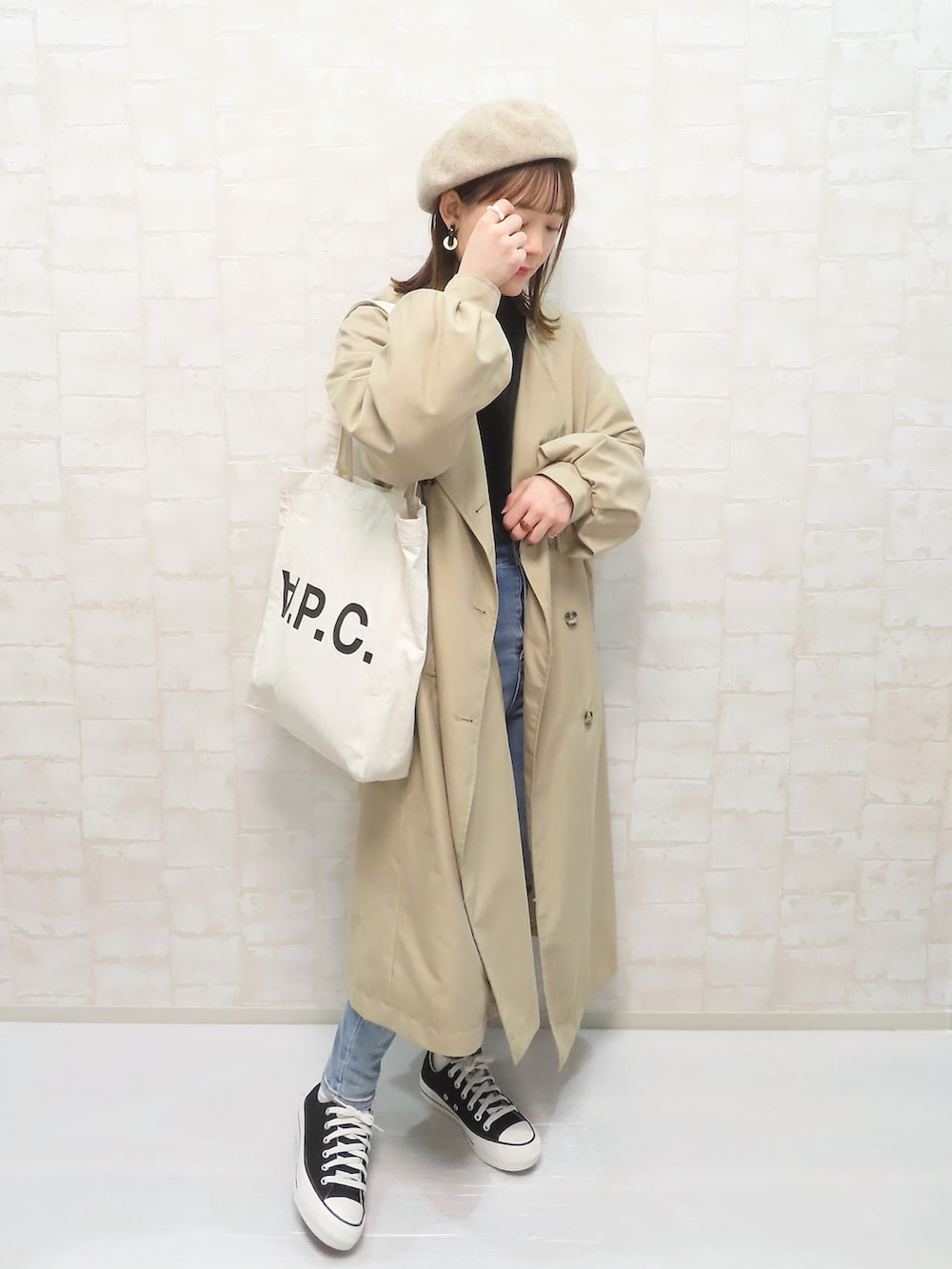 ブラック系のニット/セーター、ベージュ系のトレンチコート、ブルー系のデニムパンツを着用したレディースの冬コーディネートの2枚目の写真