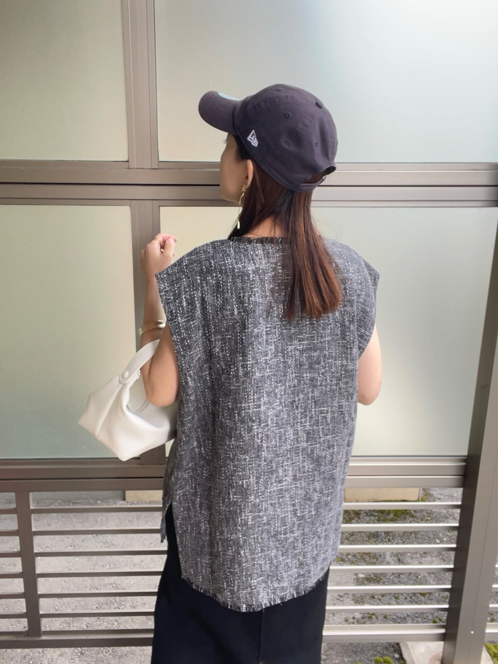 グレー系のベスト、ホワイト系のハンドバッグ、ブラック系のサンダルを着用したレディースの春コーディネートの3枚目の写真