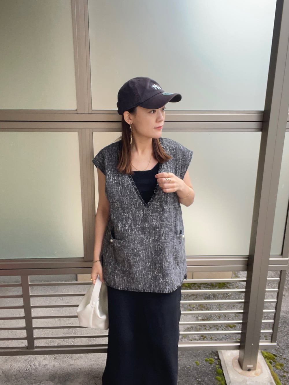 グレー系のベスト、ホワイト系のハンドバッグ、ブラック系のサンダルを着用したレディースの春コーディネートの4枚目の写真