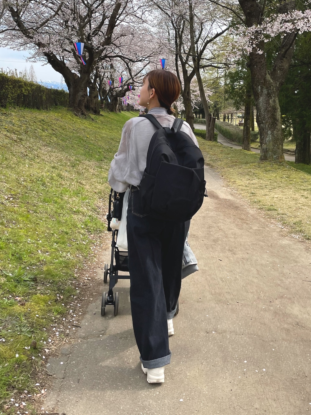 グレー系のブルゾン、ブラック系のバックパック/リュック、ブラック系のデニムパンツを着用したレディースの春コーディネートの2枚目の写真