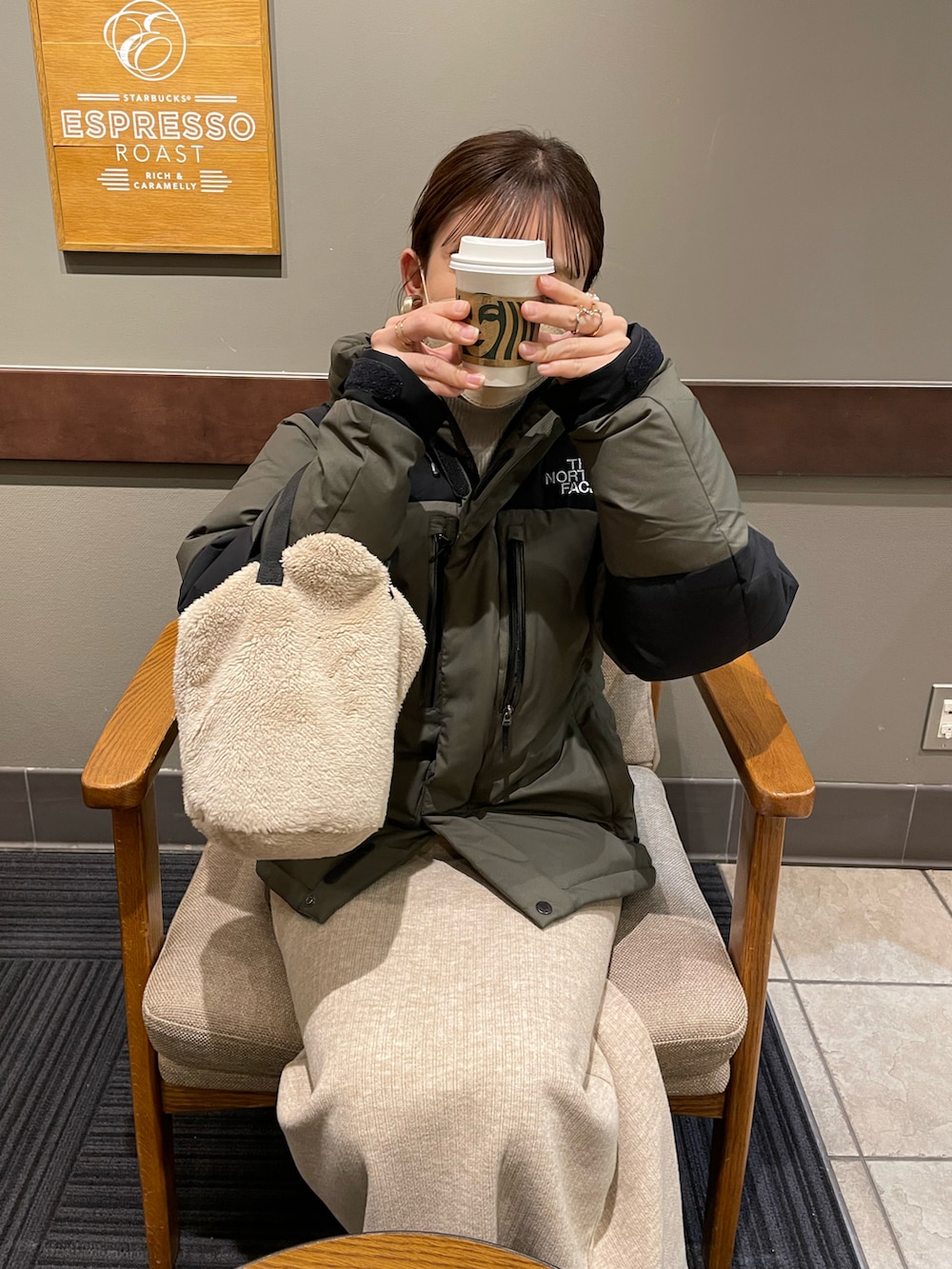 グリーン系のダウンジャケット/コート、ホワイト系のニット/セーター、ベージュ系のスカートを着用したレディースの冬コーディネートの5枚目の写真