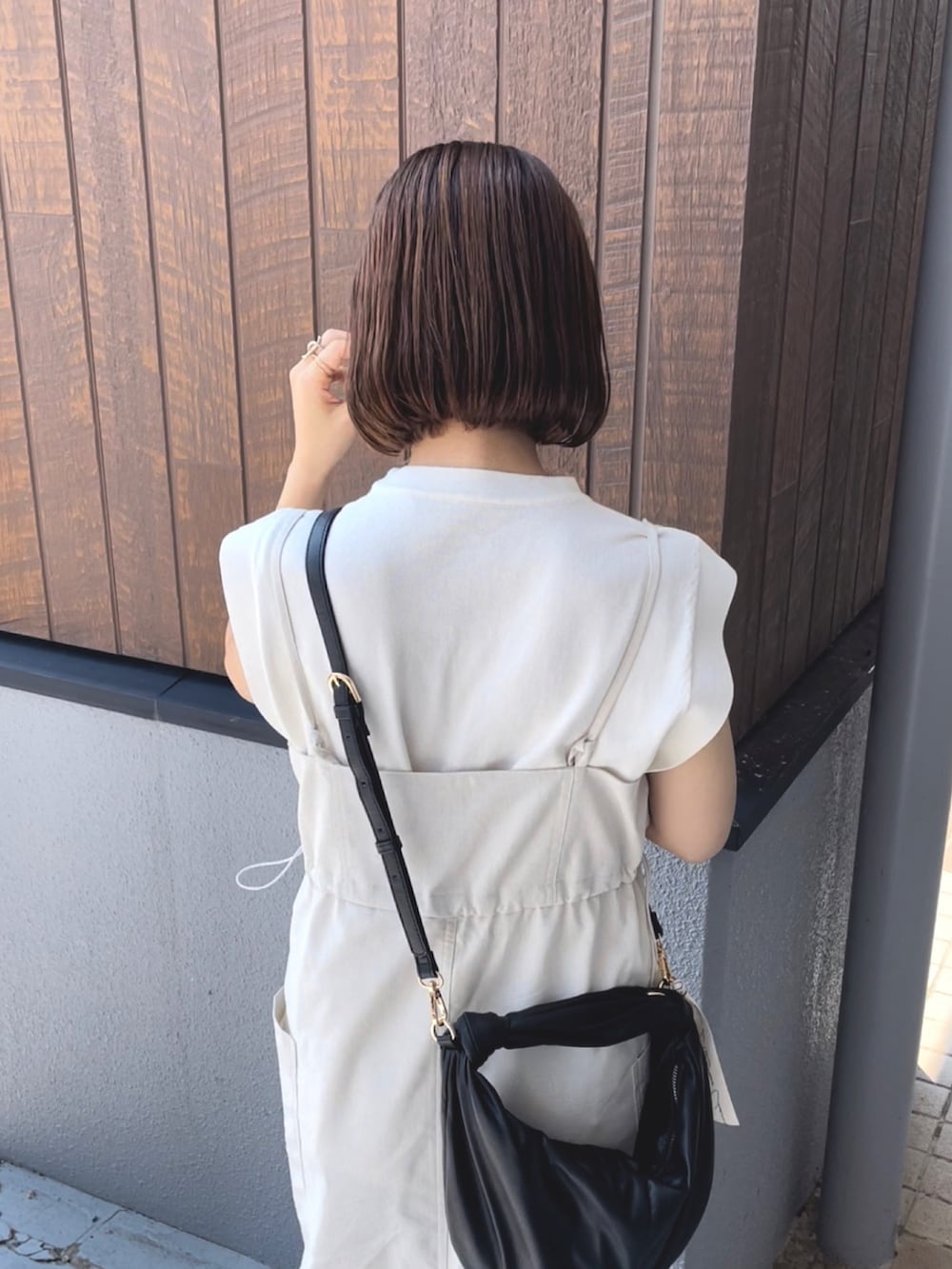 ベージュ系のワンピース/ドレス、ホワイト系のニット/セーター、ブラック系のハンドバッグを着用したレディースの夏コーディネートの3枚目の写真