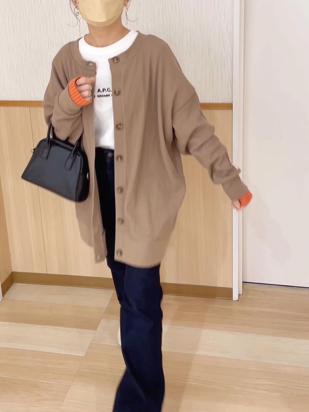 ブラウン系のカーディガン/ボレロ、ブルー系のデニムパンツ、ホワイト系のスニーカーを着用したレディースの春コーディネートの2枚目の写真