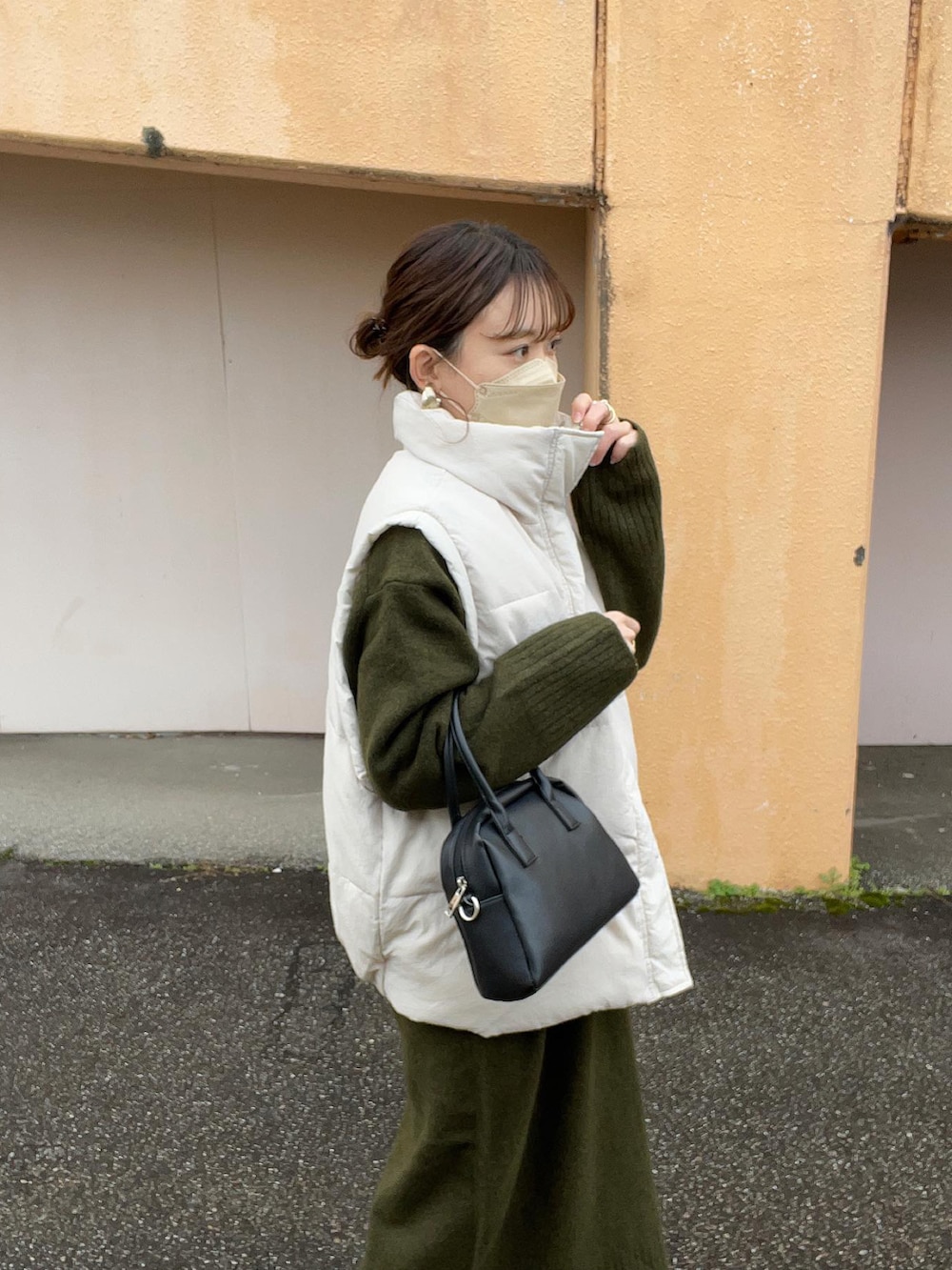 グリーン系のワンピース、ホワイト系のニット/セーター、ホワイト系のダウンベストを着用したレディースの冬コーディネートの4枚目の写真