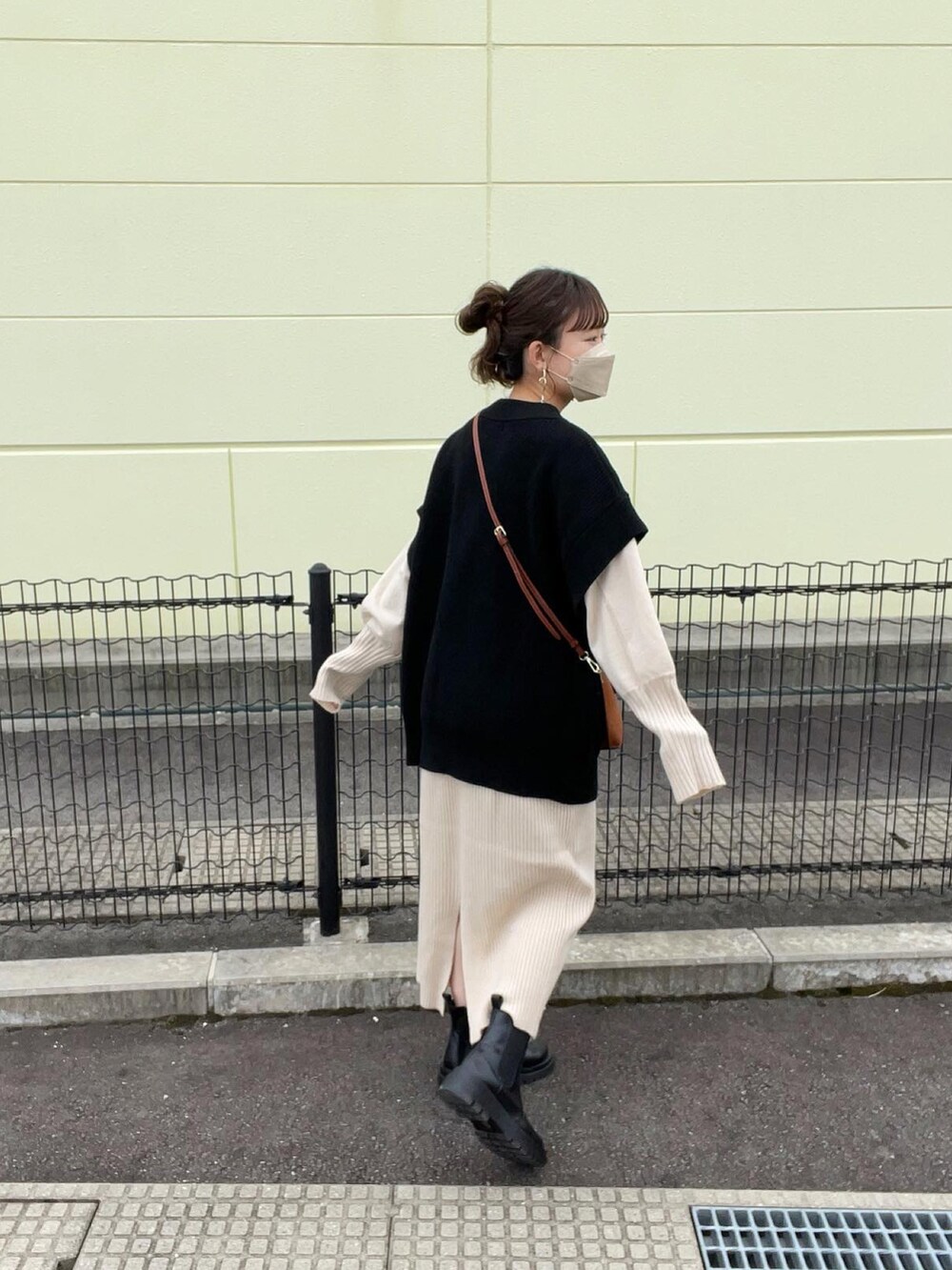 ブラック系のベスト、ホワイト系のワンピース、ブラウン系のショルダーバッグを着用したレディースの秋コーディネートの2枚目の写真