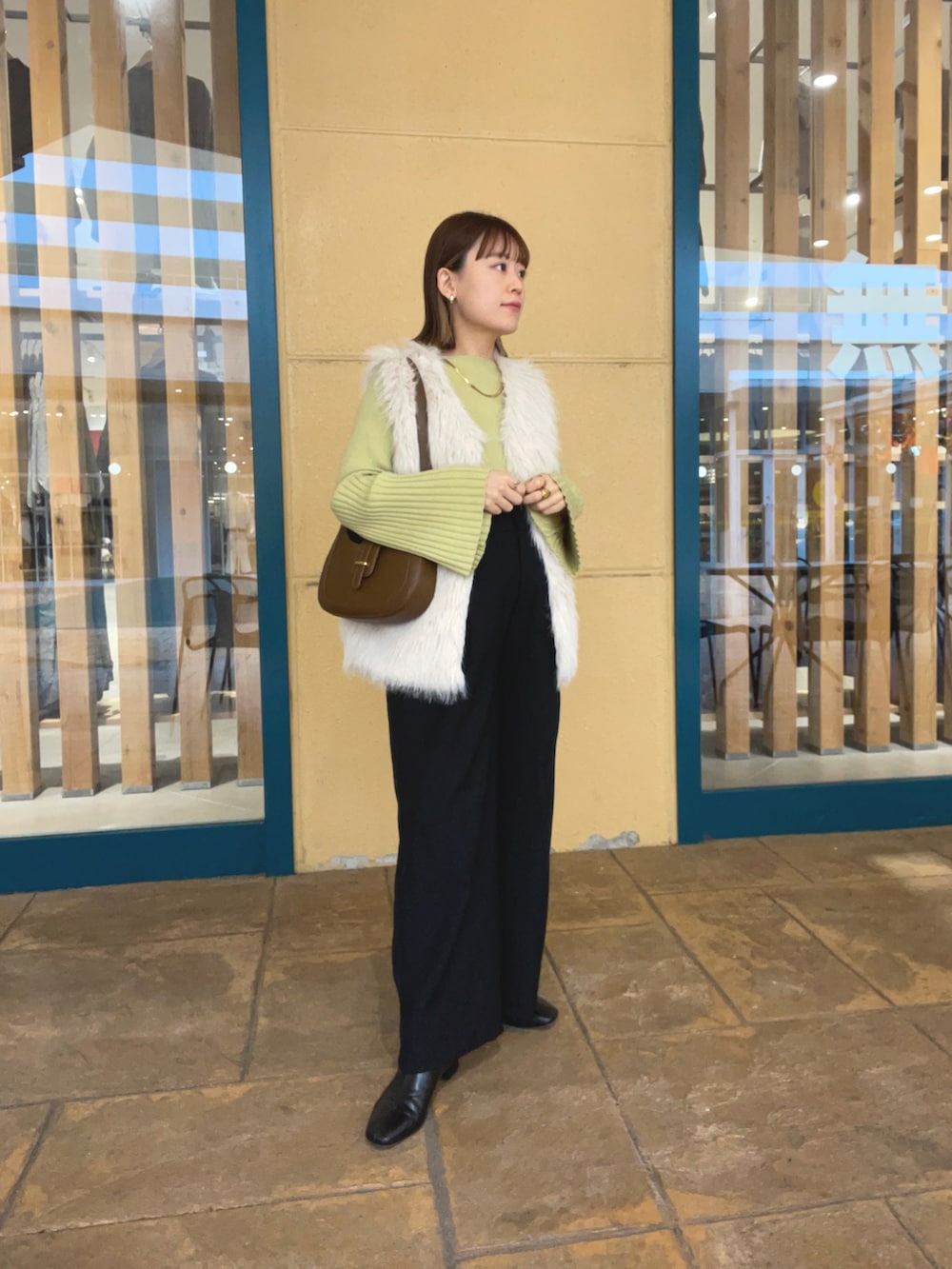 グリーン系のニット/セーター、ホワイト系のベスト、ブラック系のパンツを着用したレディースの秋コーディネートの3枚目の写真